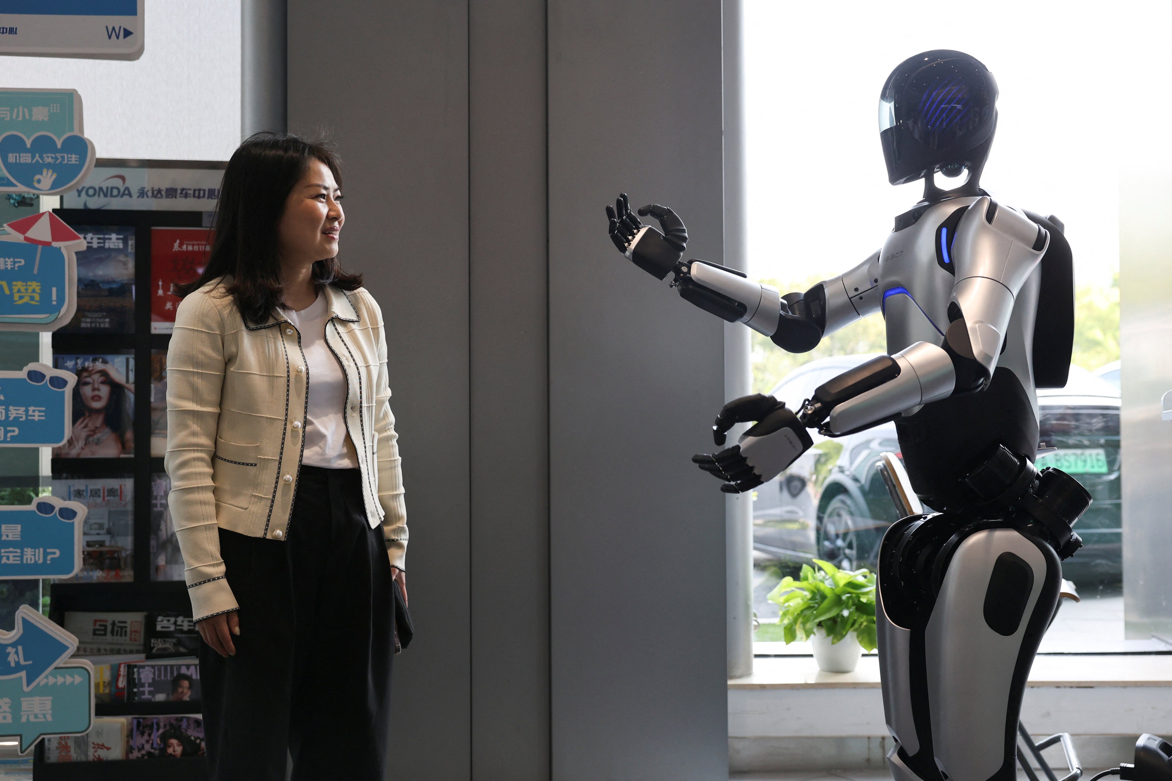A customer interacts with an AgiBot humanoid at a car dealership in Shanghai, April 8, 2025. Photo: Reuters