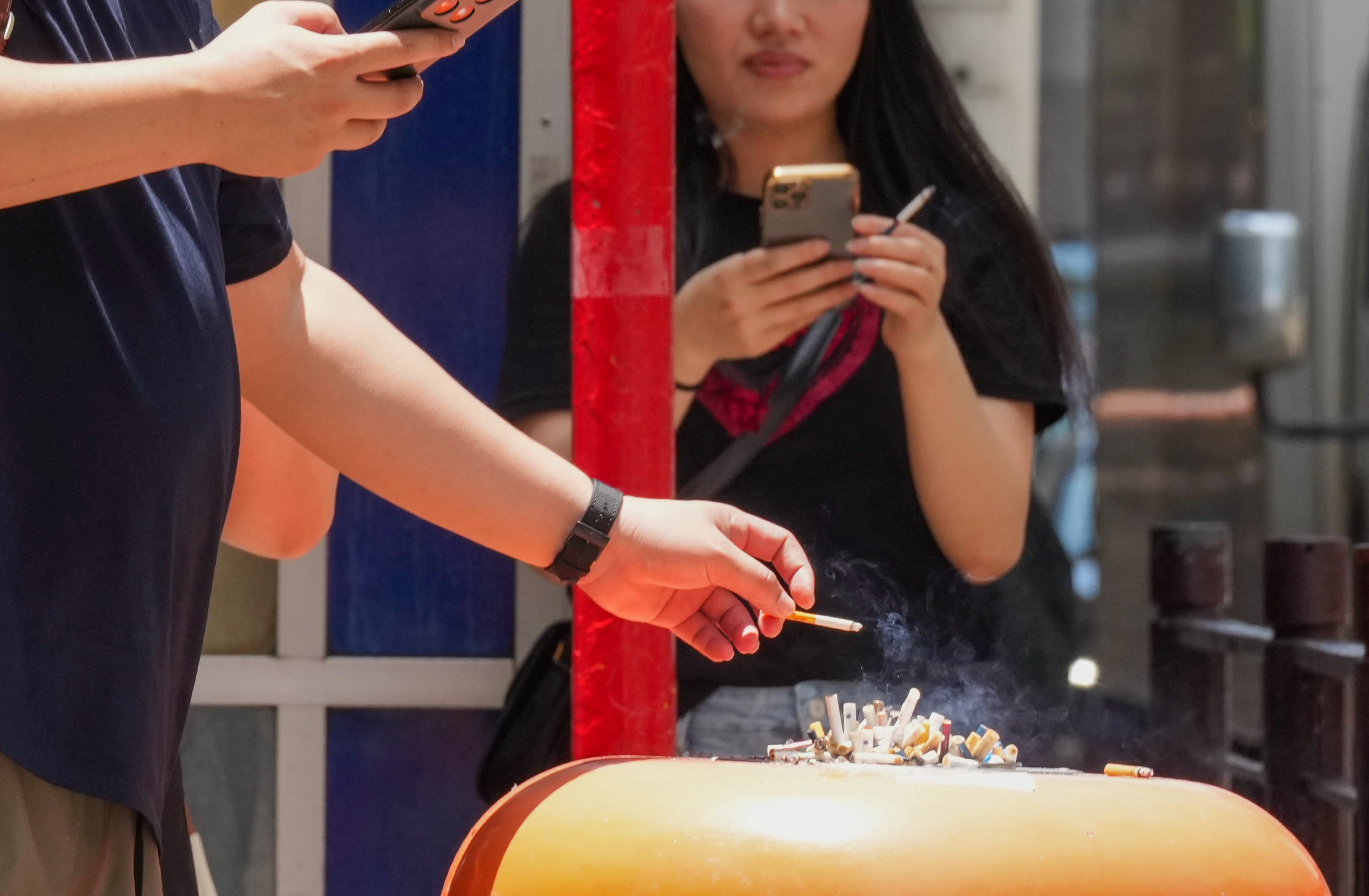 People smoke beside a rubbish bin in Tsim Sha Tsui on May 27. Photo: Jelly Tse