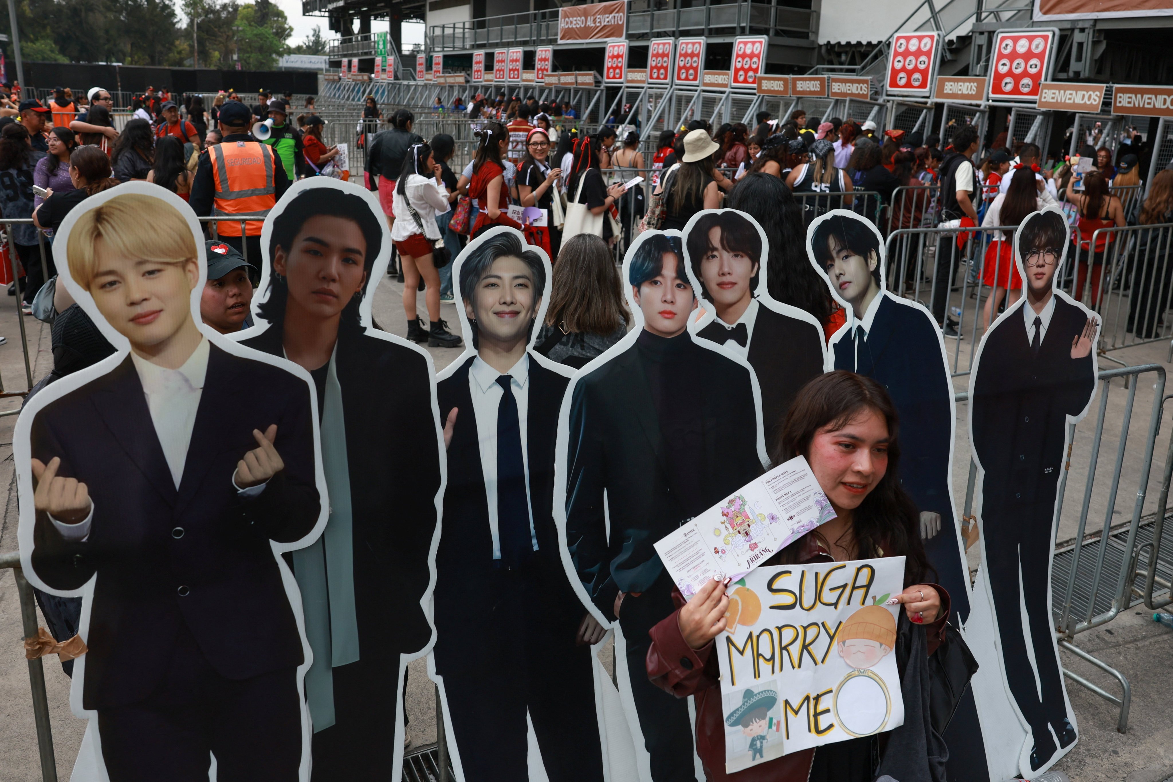A fan poses with cardboard cut-outs of BTS members outside a concert venue in Mexico City on May 7. Photo: Reuters