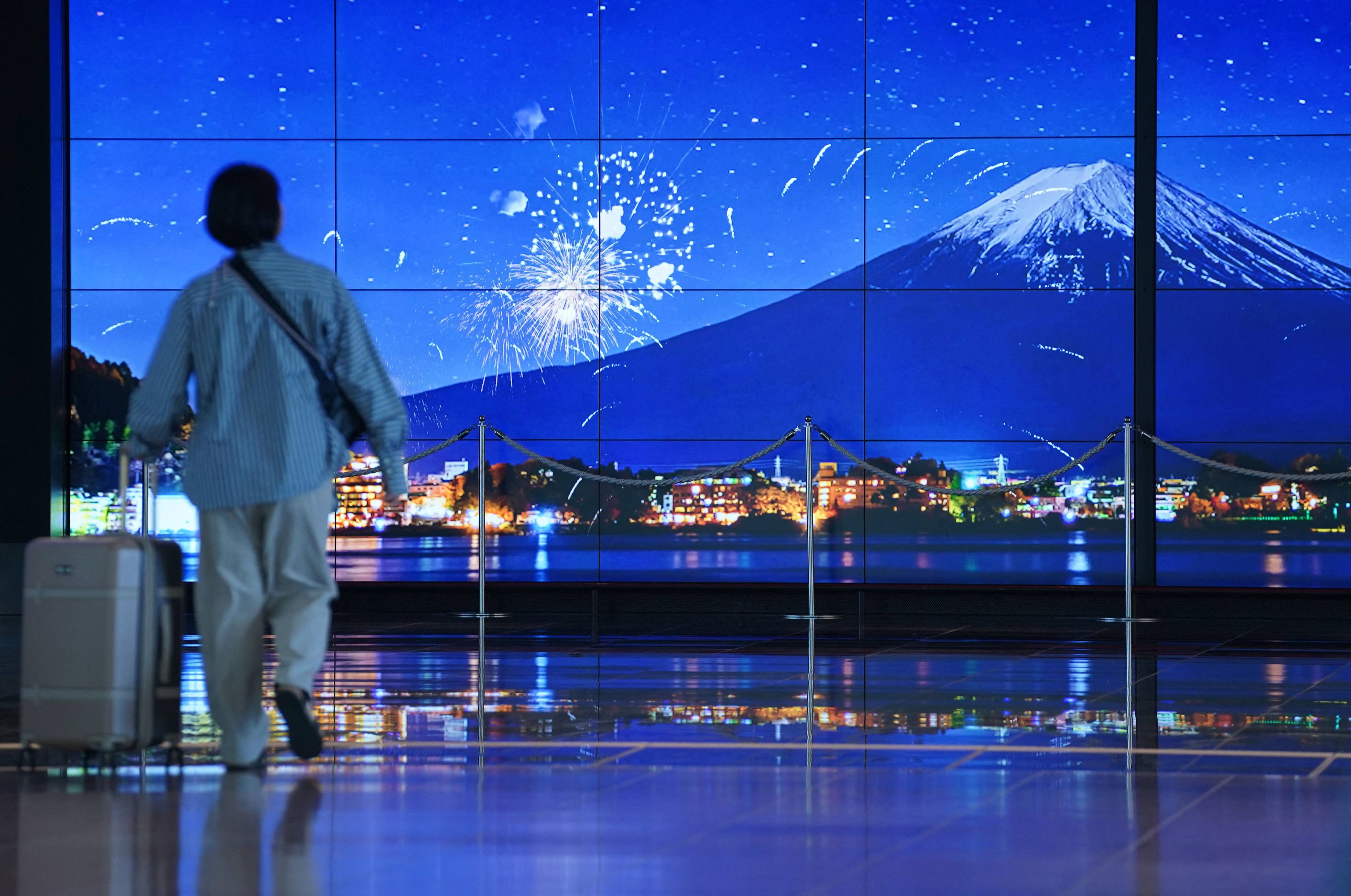 A traveller walks past an image of Mount Fuji in the arrivals terminal at Haneda Airport in Tokyo on May 20. Photo: AFP