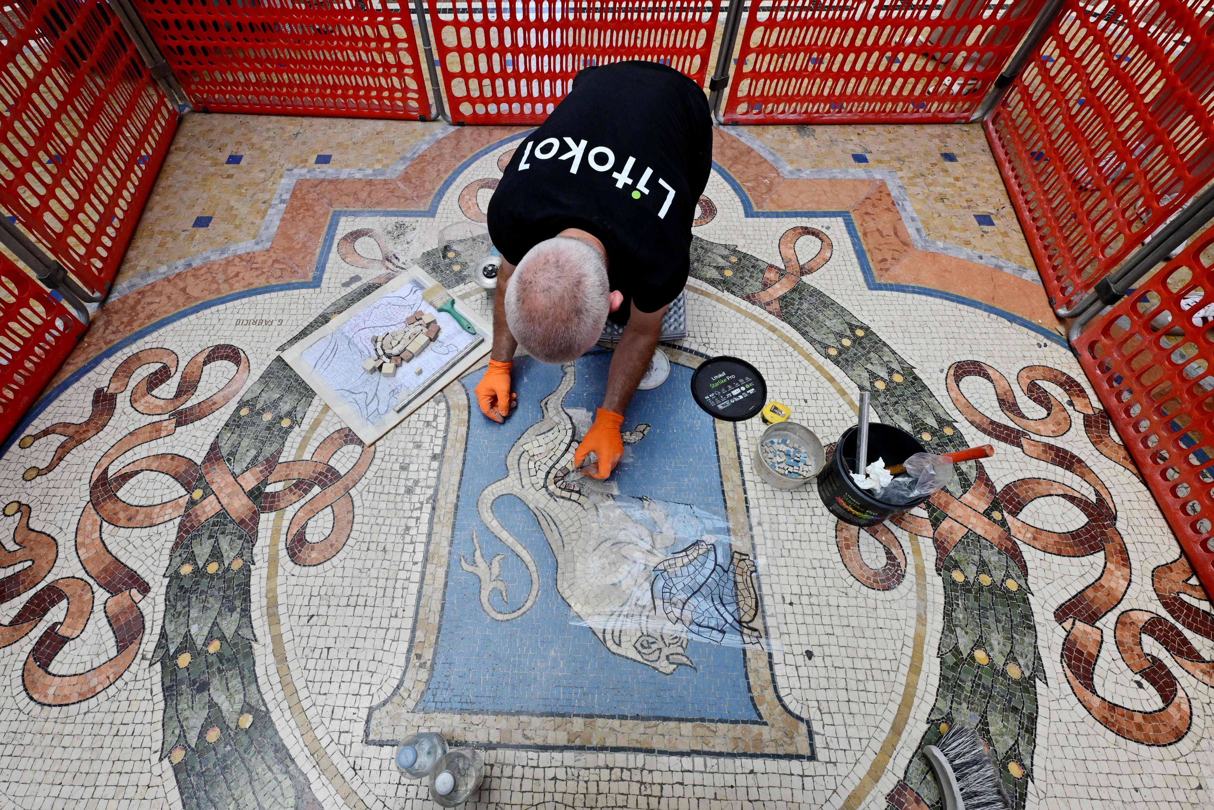 Restorer Gianluca Galli works on the mosaic of the bull during the restoration in the Galleria Vittorio Emanuele II, Milan, Italy on Thursday. Photo:  AFP