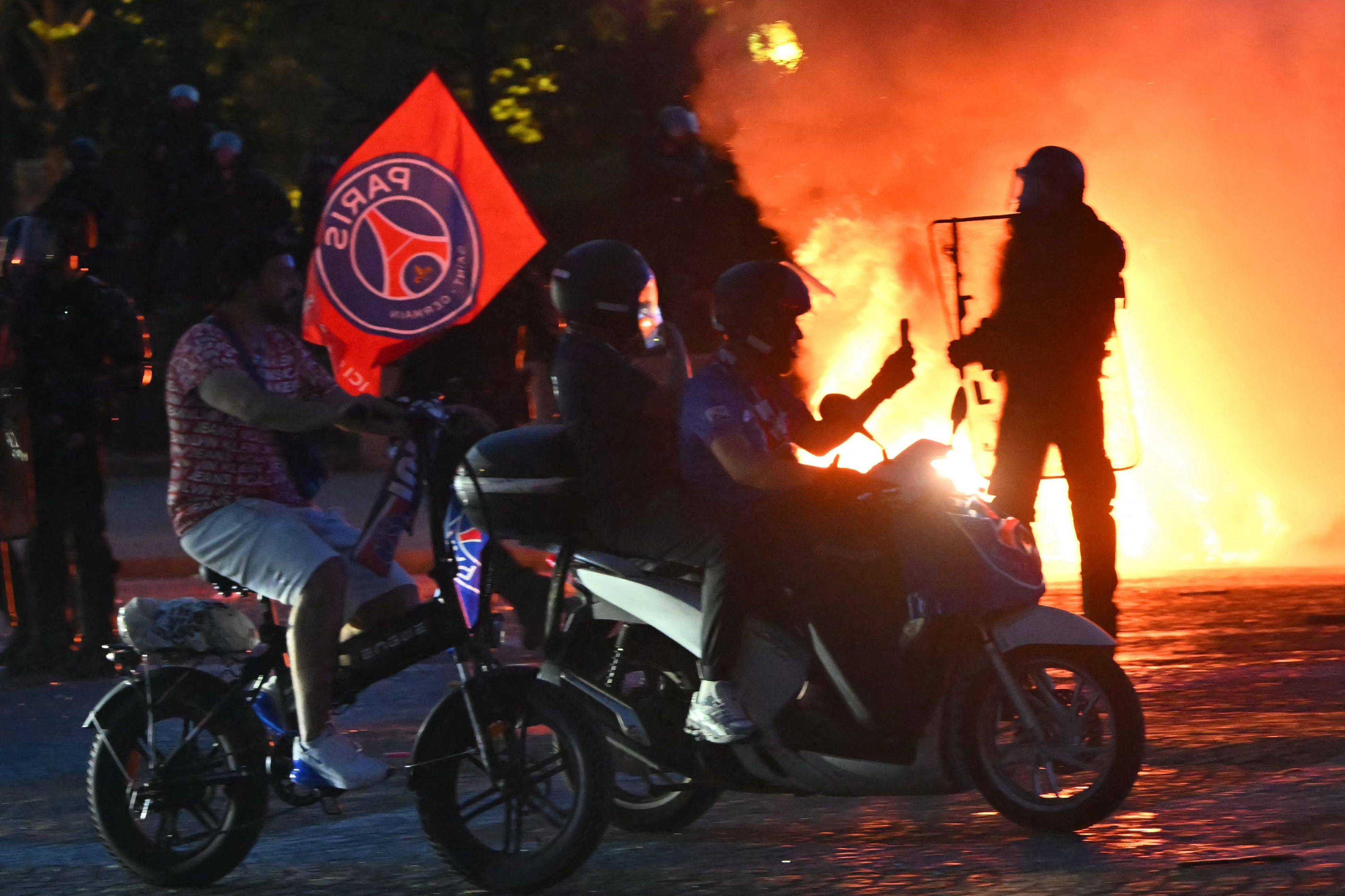 PSG supporters drive their scooters past anti-riot police officers (right) as they celebrate their team’s win in the UEFA Champions League final, in Paris on Saturday. Photo: AFP