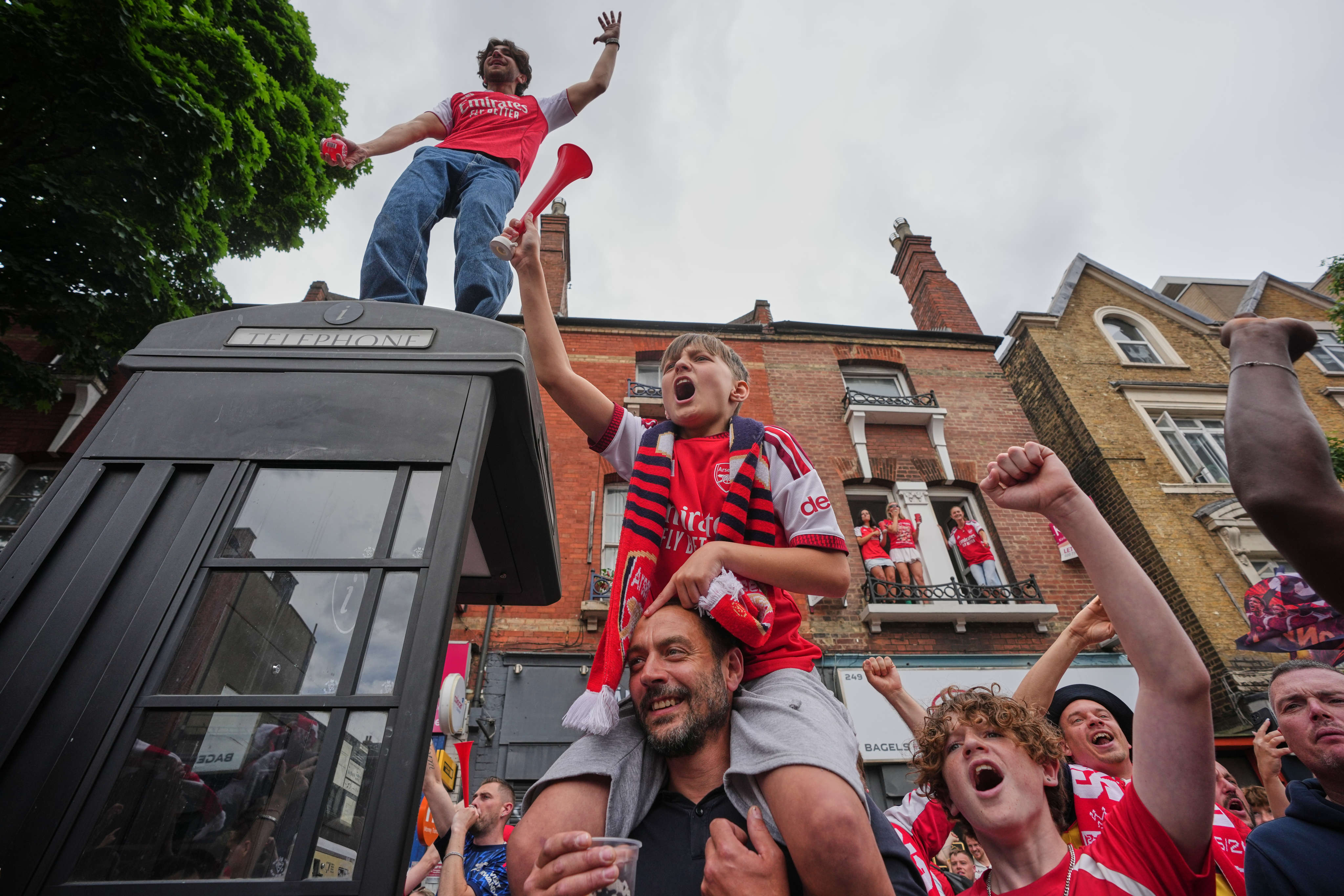 Arsenal fans celebrate as they wait for the buses to pass by carrying the team during a parade for winning the English Premier League title, in London on Sunday. Photo: AP
