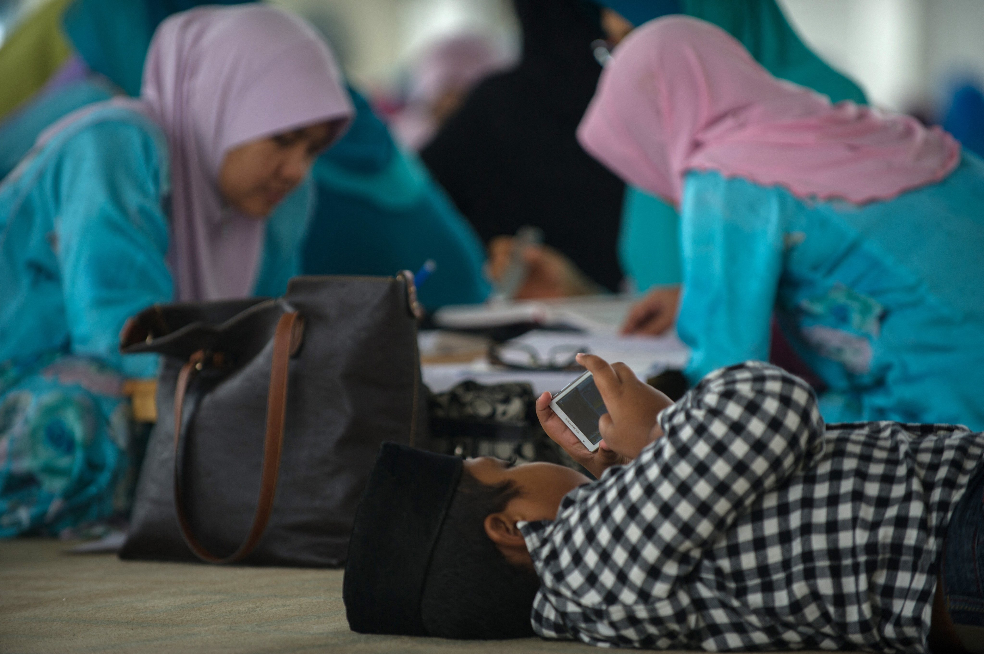 A young boy plays with a phone inside a mosque in Putrajaya, Malaysia. Photo: AFP