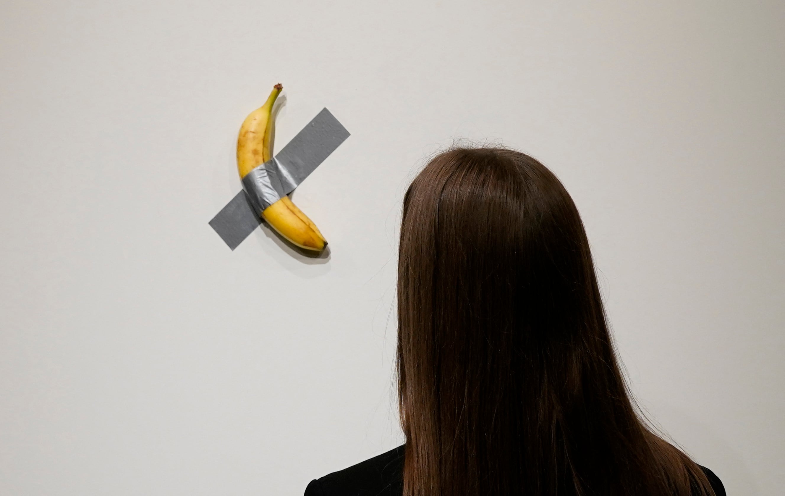 A person looks at Italian visual artist Maurizio Cattelan’s duct-taped banana entitled “Comedian,” during a press preview at Sotheby’s in New York, on October 25, 2024. Photo: AFP