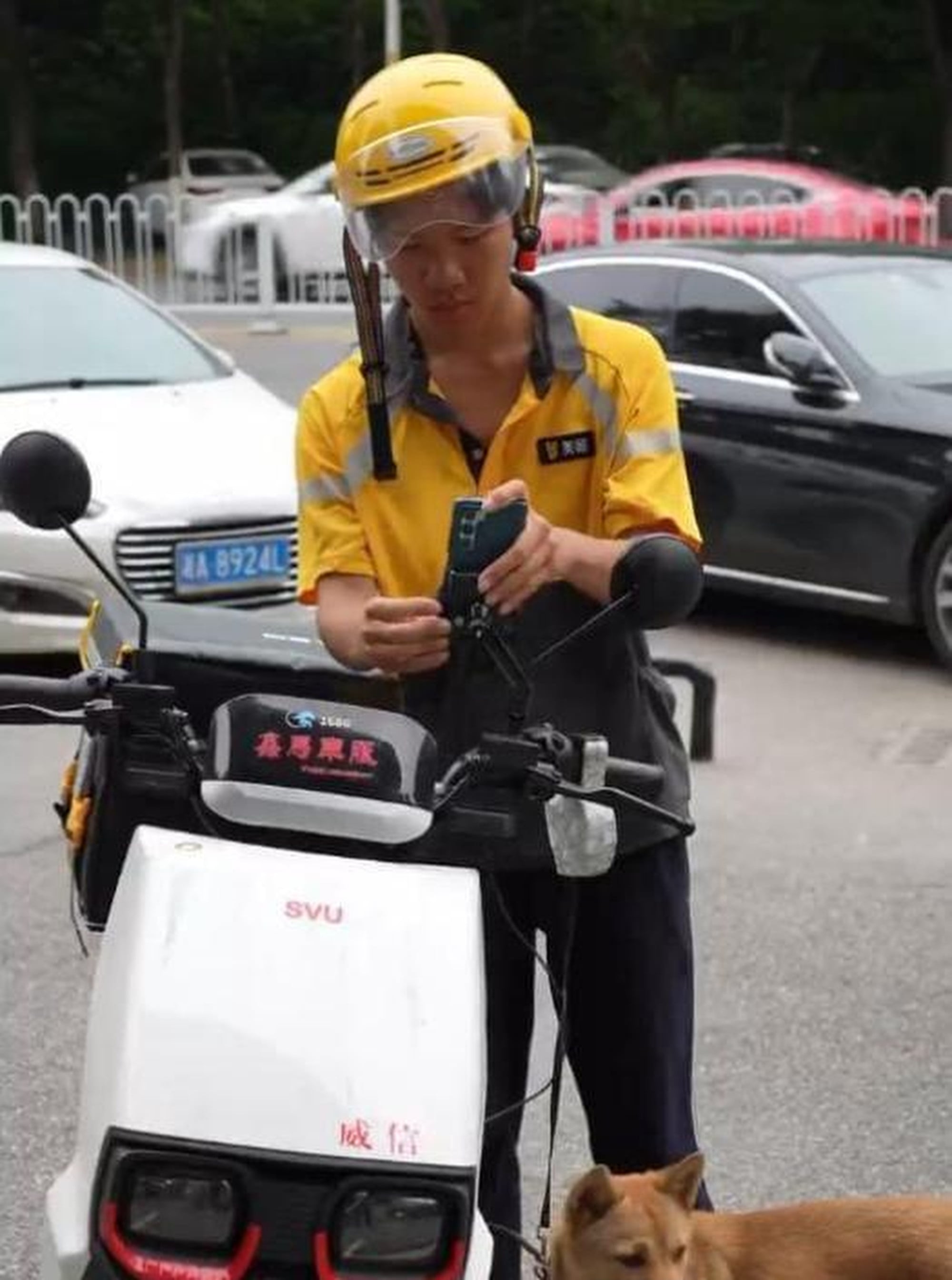 Tang, above, checks his mobile phone while leaning on his electric bicycle with Bobo by his side. Photo: Handout
