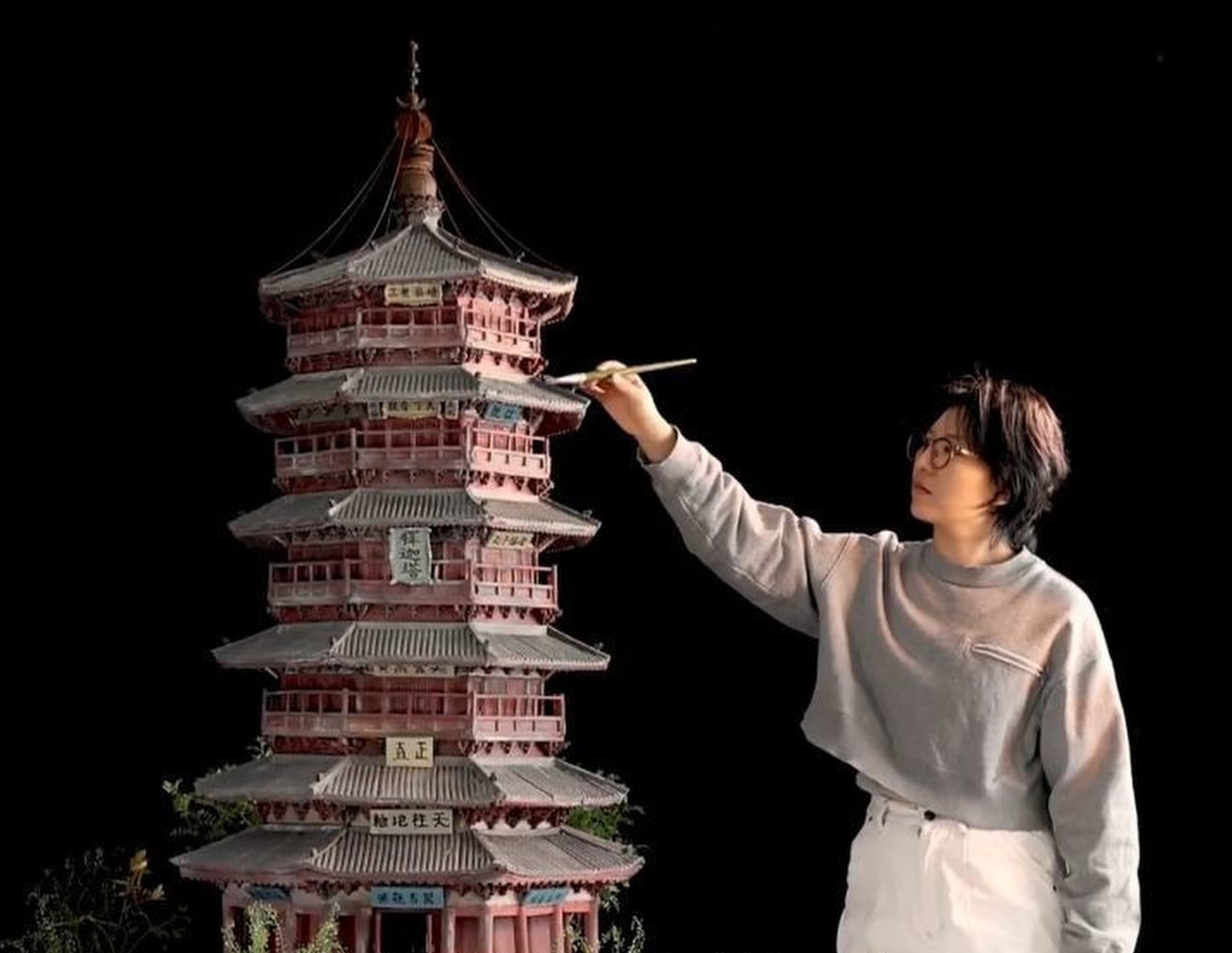 Fan Sumu puts the finishing touches to a pagoda using a paintbrush. Photo: ctdsb.net