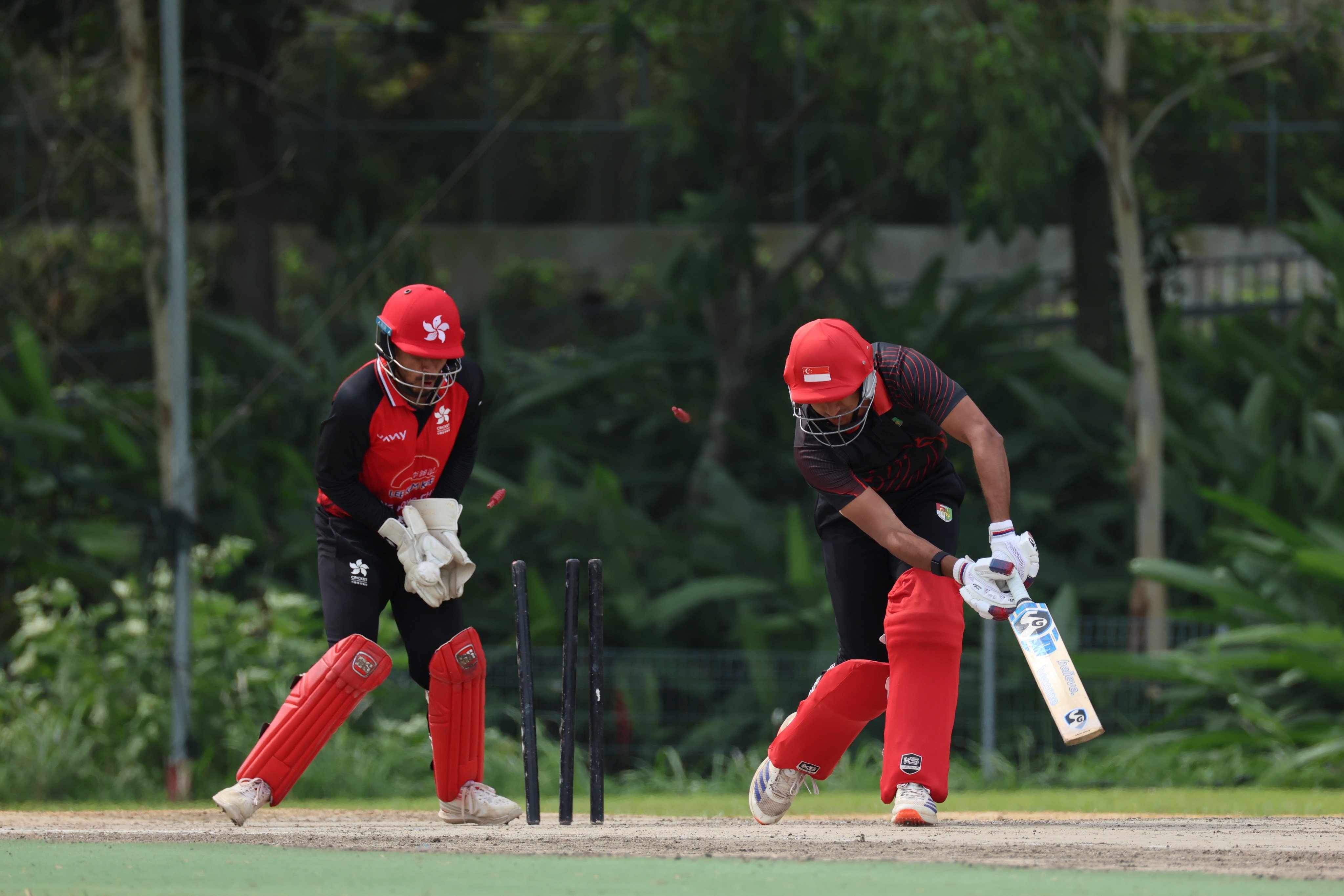 Hong Kong wicketkeeper Shahid Wasif (left) watches on as another Singapore wicket falls to the leg spin of Mohammad Ghazanfar. Photo: Handout