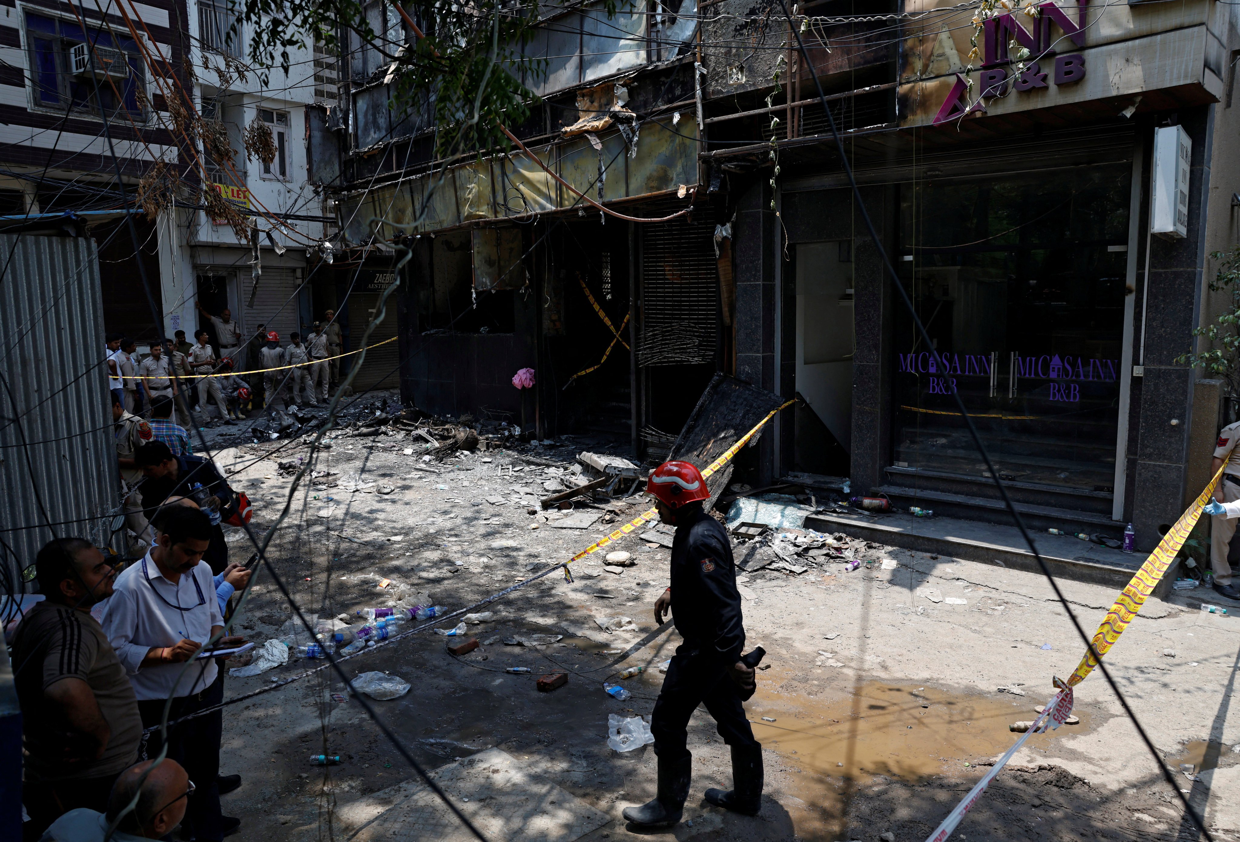 Firefighters and police officers work at the site after a fire at a hotel in New Delhi, India on Wednesday. Photo: Reuters