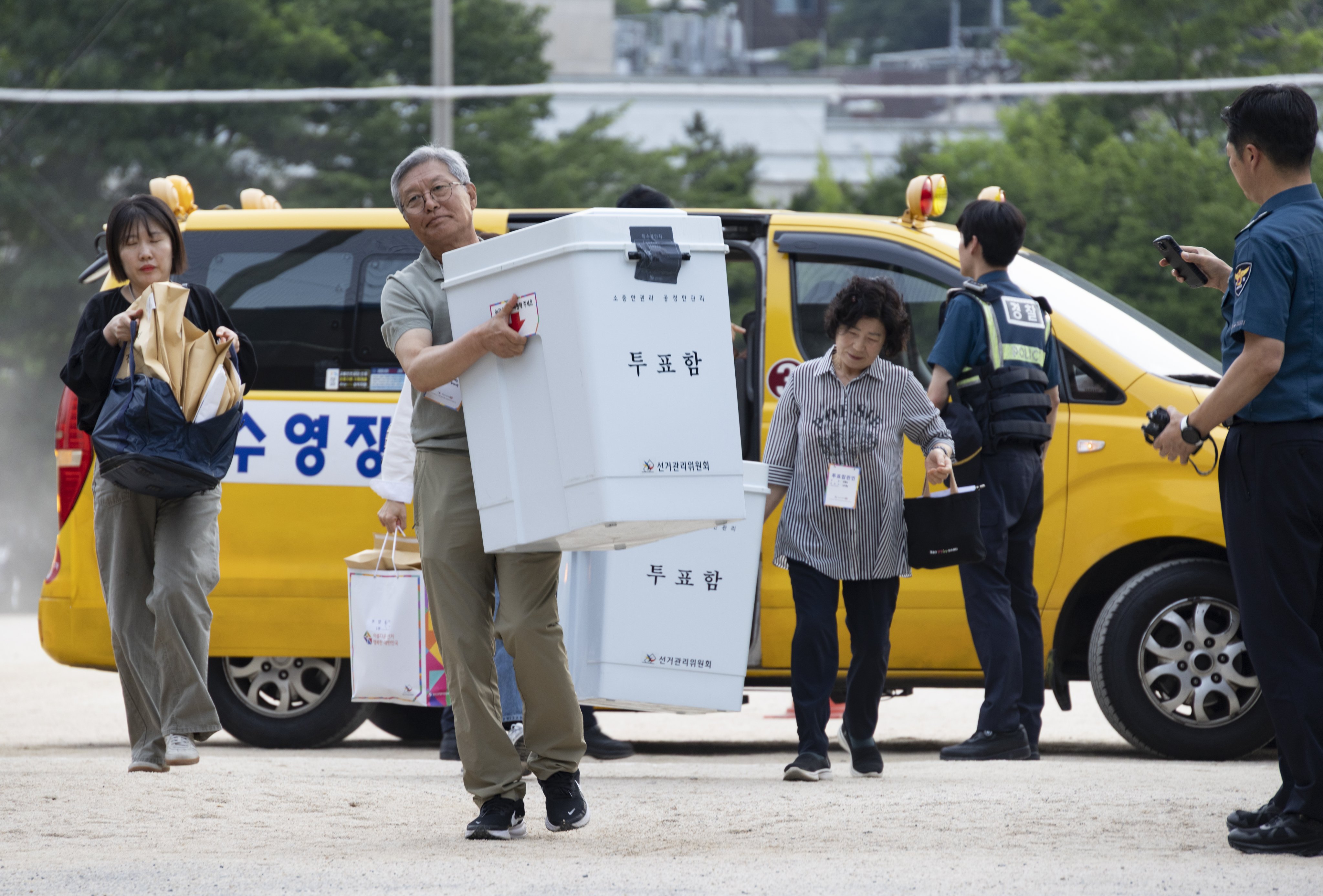 Election officials carry ballot boxes at a counting station in Seoul after voting in the national local elections closed on Wednesday. Photo: EPA