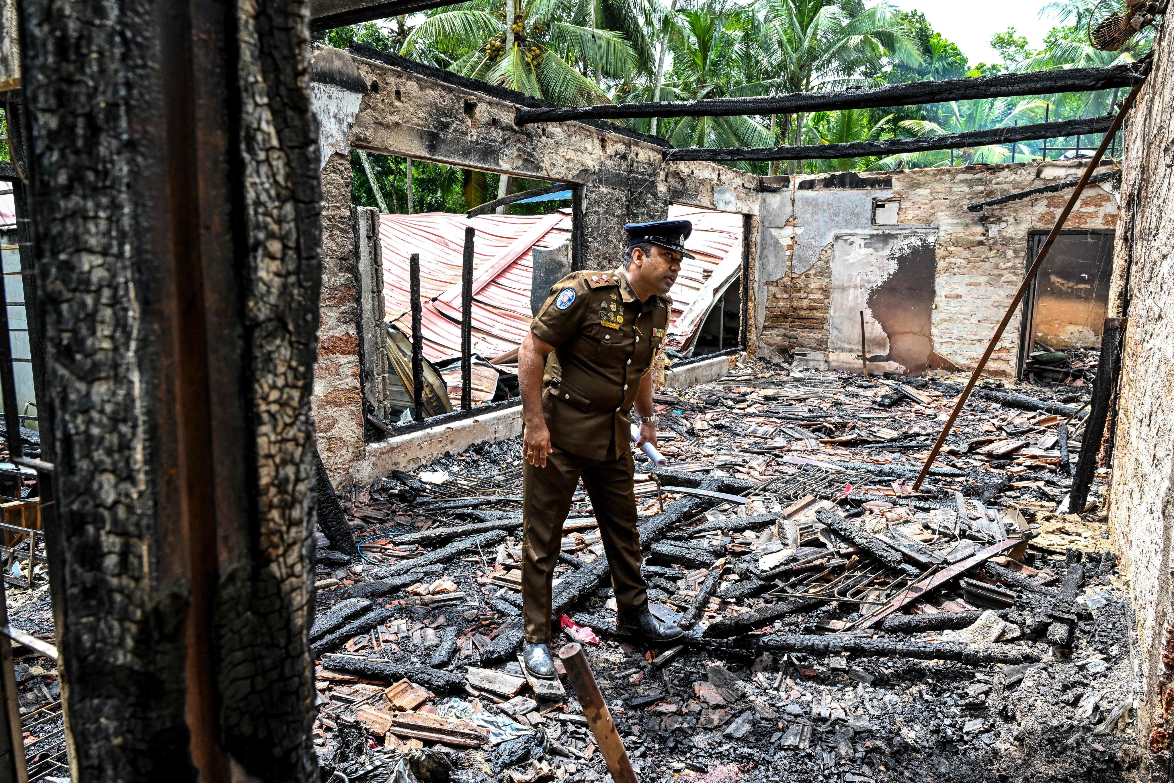 A police personnel inspects the burnt house on Thursday, a day after a fire broke out at an elder care home in Sri Lanka’s Batagoda. Photo: AFP