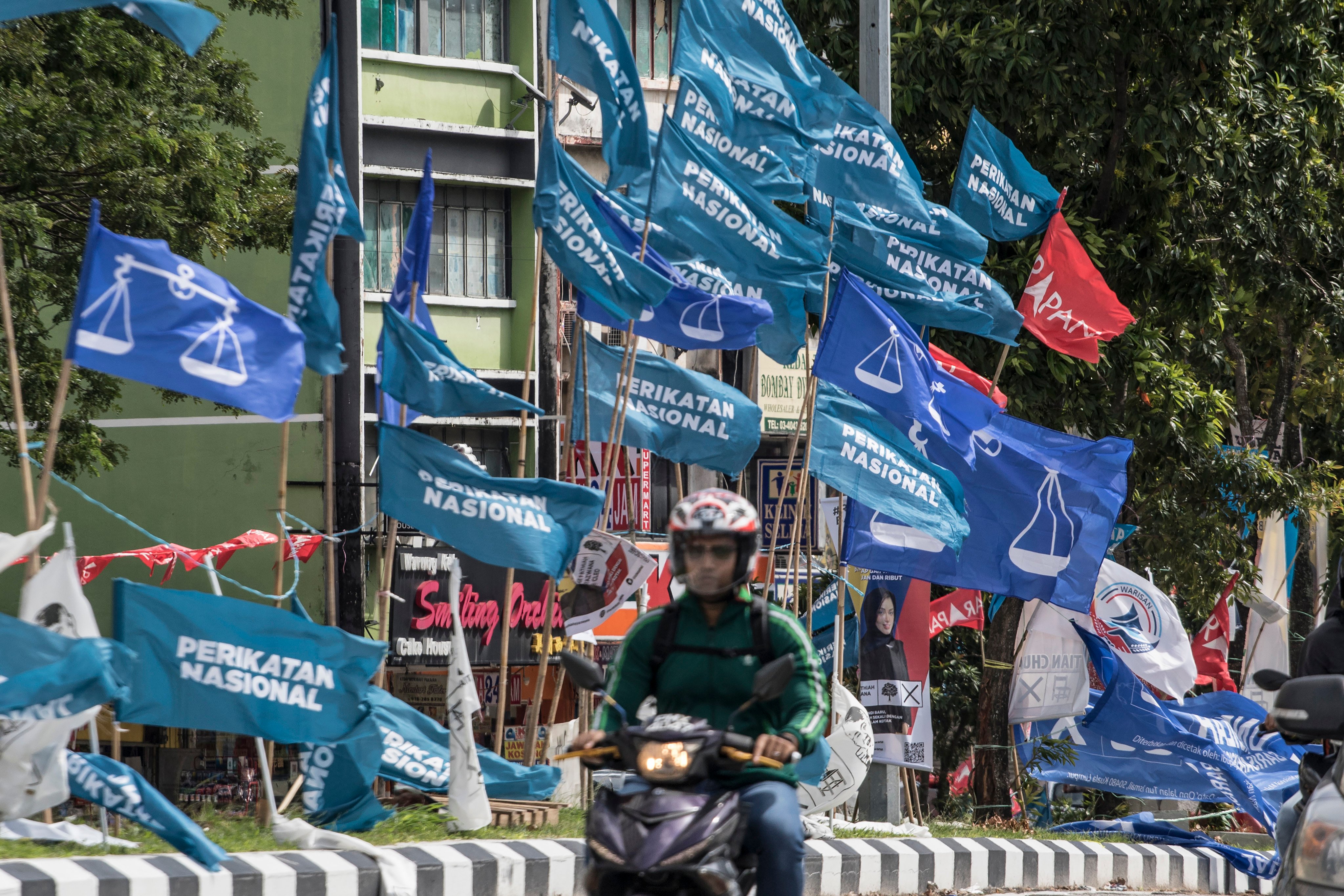 A motorcycle passes campaign flags of Malaysia’s Barisan Nasional (blue) and Pakatan Harapan (red) coalitions displayed in Kuala Lumpur in 2022. Photo: AP