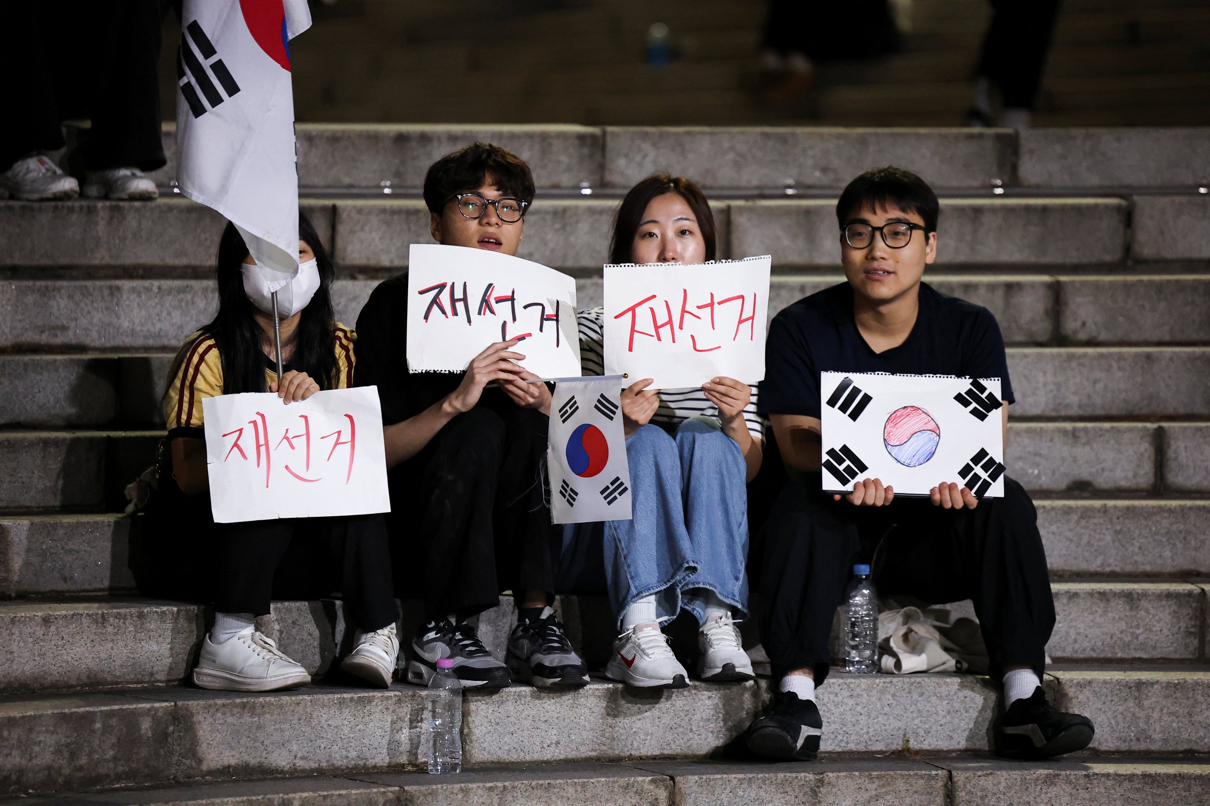 Demonstrators hold signs reading “Rerun election”, as people surround a vote-counting centre during a protest in Seoul on Saturday. Photo: Reuters