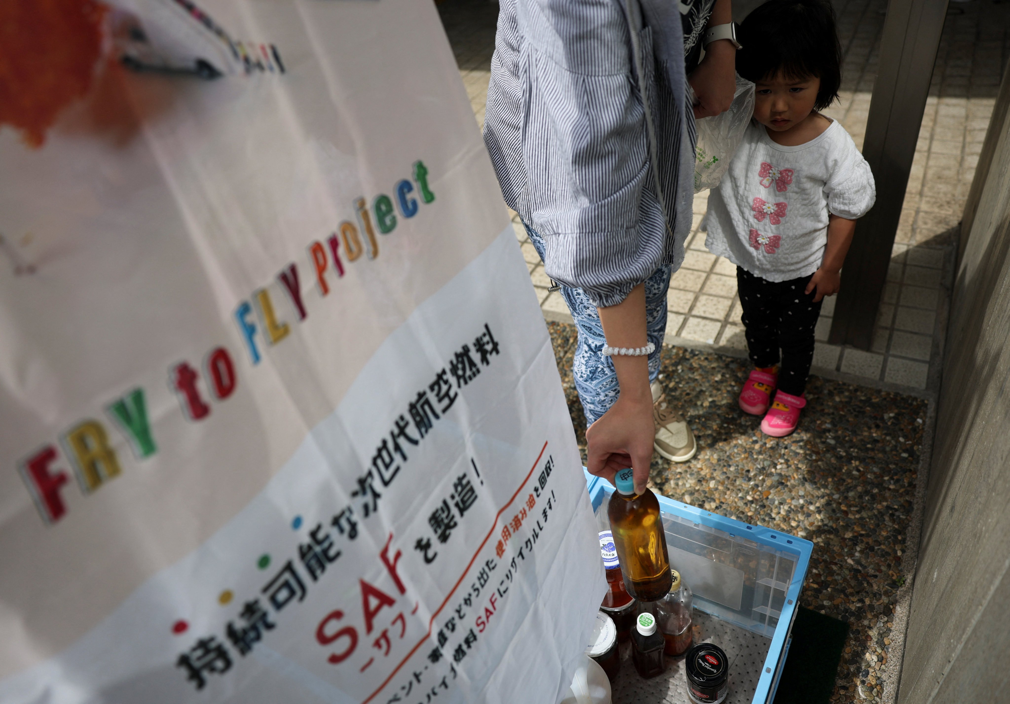 A woman brings used cooking oil to a waste oil collection point for Japan’s “Fry to Fly” project in Adachi ward, Tokyo, on April 18. Photo: Reuters