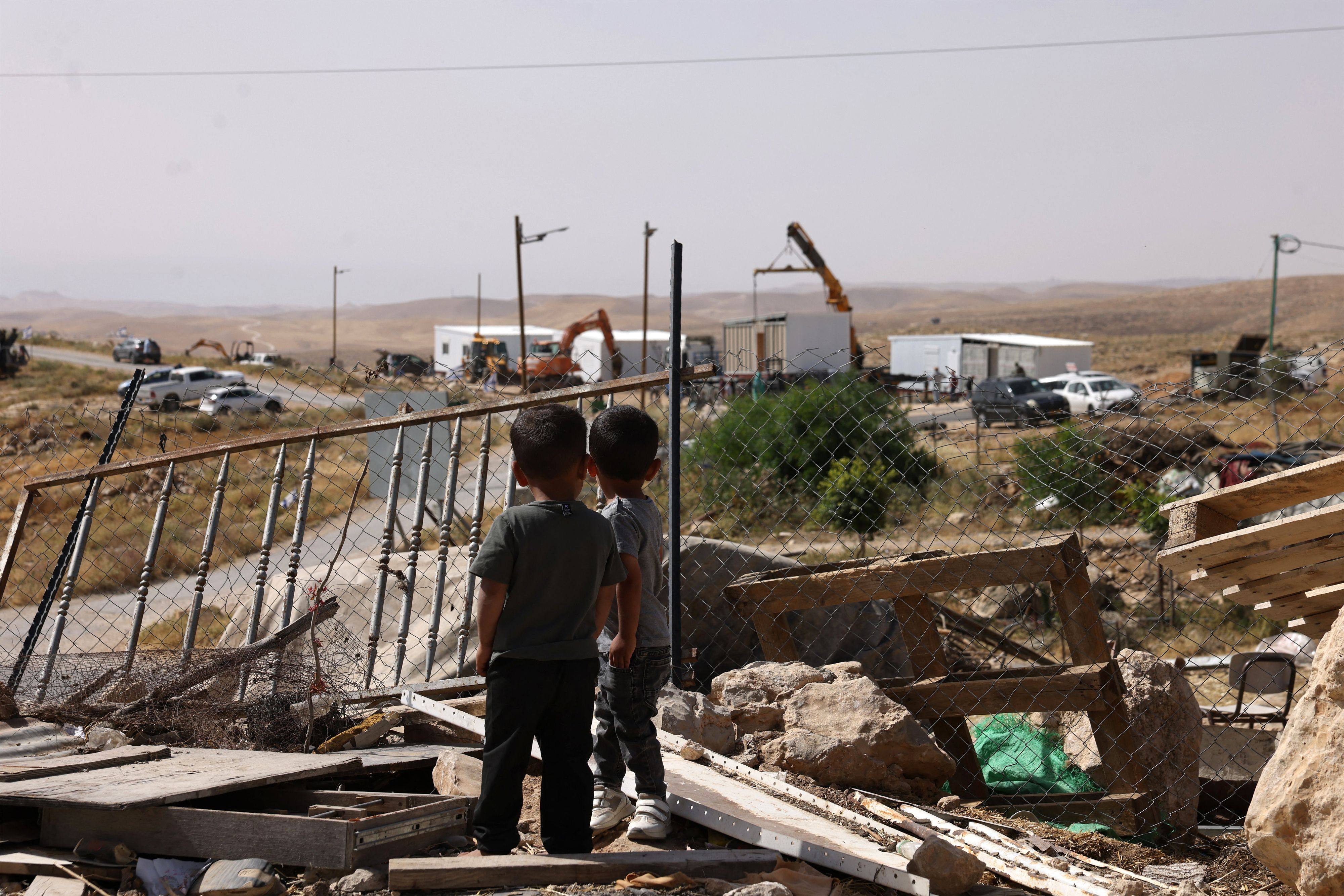 Children watch as new prefabricated Jewish homes are secured into placed along a road that leads toward the Palestinian village of Umm al-Khair on May 20. Photo: AFP