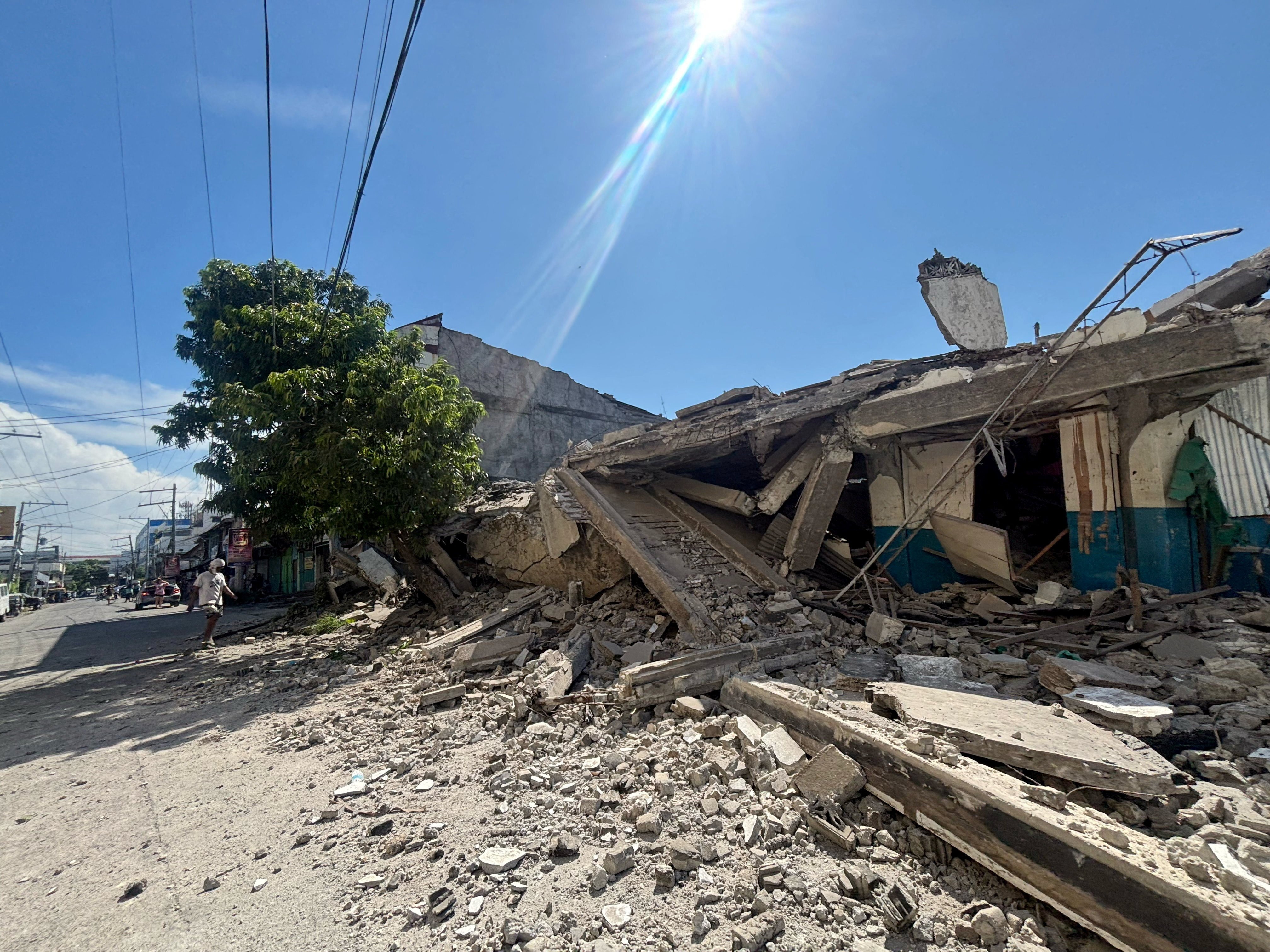 A man walks near a collapsed building after a magnitude 7.8 quake in General Santos, Mindanao Island, the Philippines, on Monday. Photo: GenSan Dev/Reuters