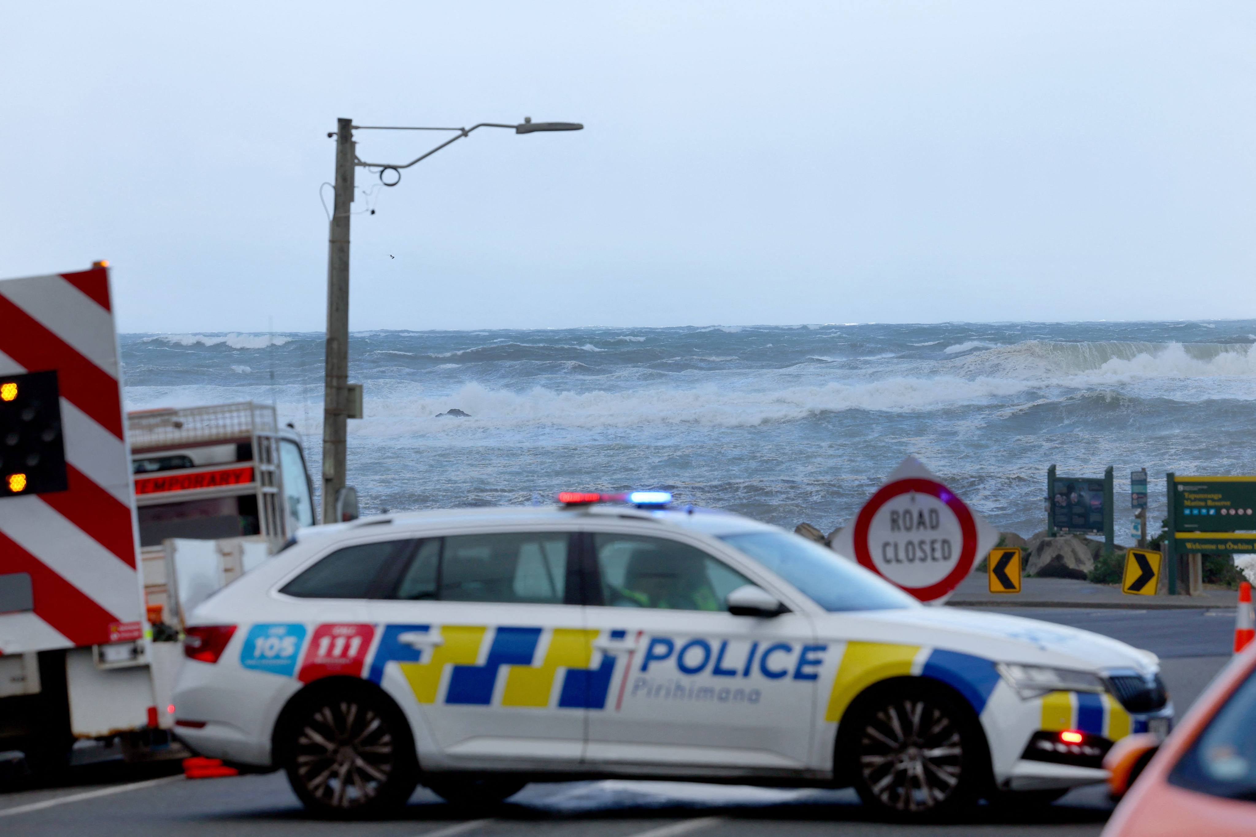 A police car is seen parked across a closed road as stormy seas pound the coastline of Owhiro Bay, a suburb of New Zealand’s capital Wellington, on Tuesday. Photo: AFP