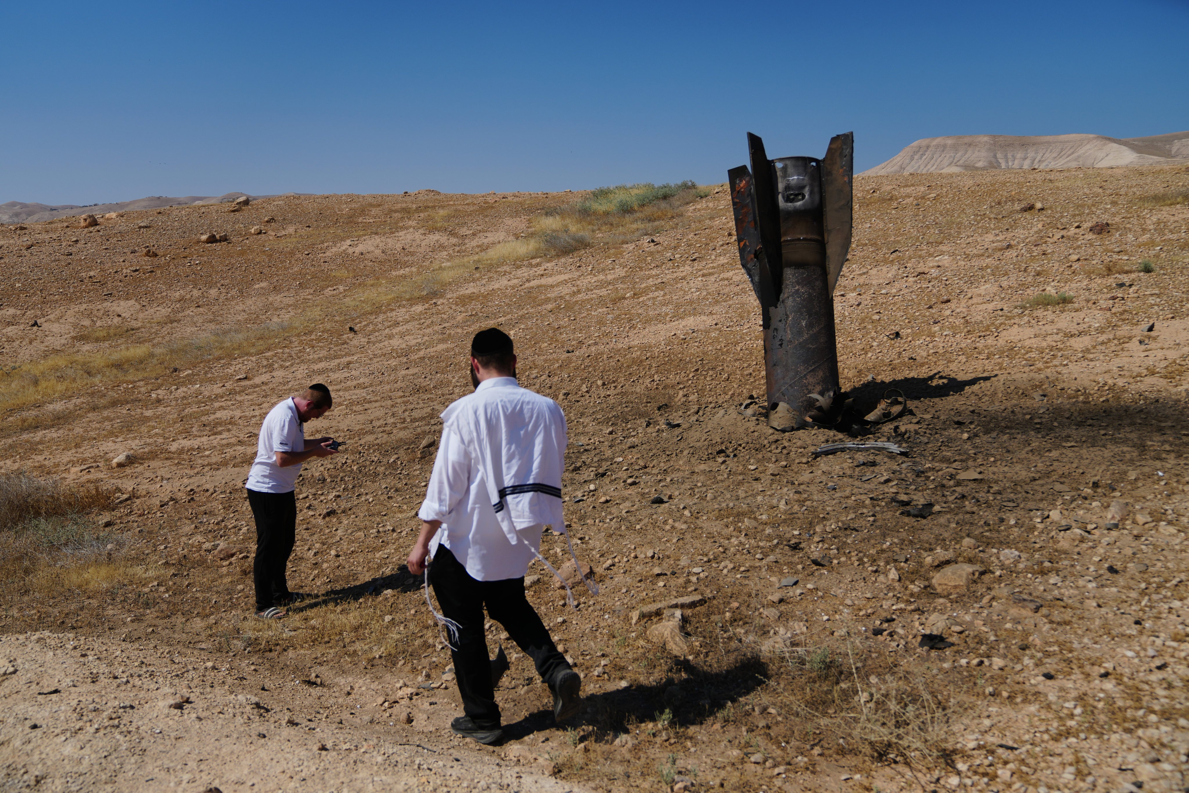 People take photos of the wreckage of an Iranian missile that landed near the West Bank city of Jericho on Monday. Photo: AP