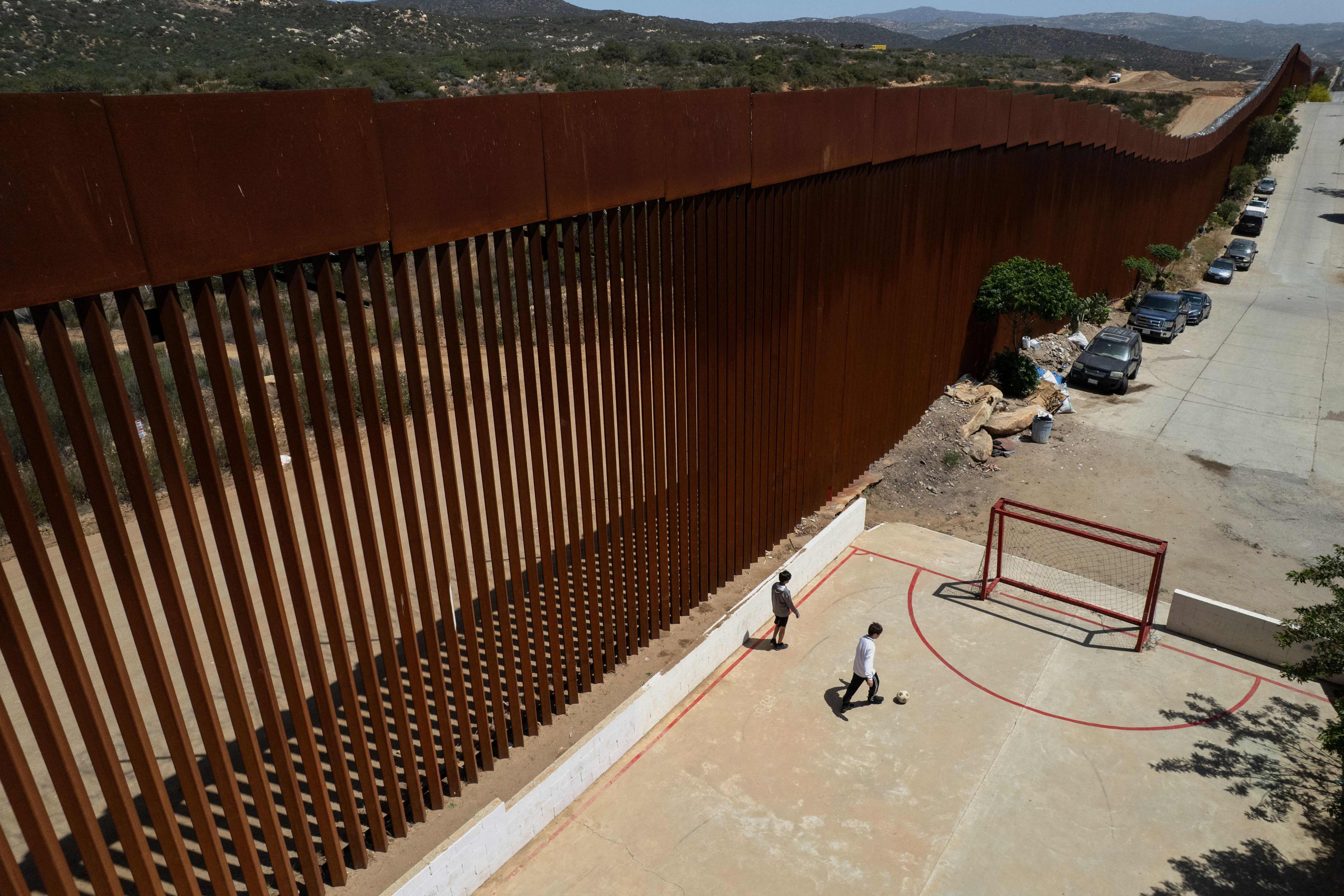 Children play football on a court next to the border wall in Tecate, Baja California state, Mexico, in April. Photo: AFP
