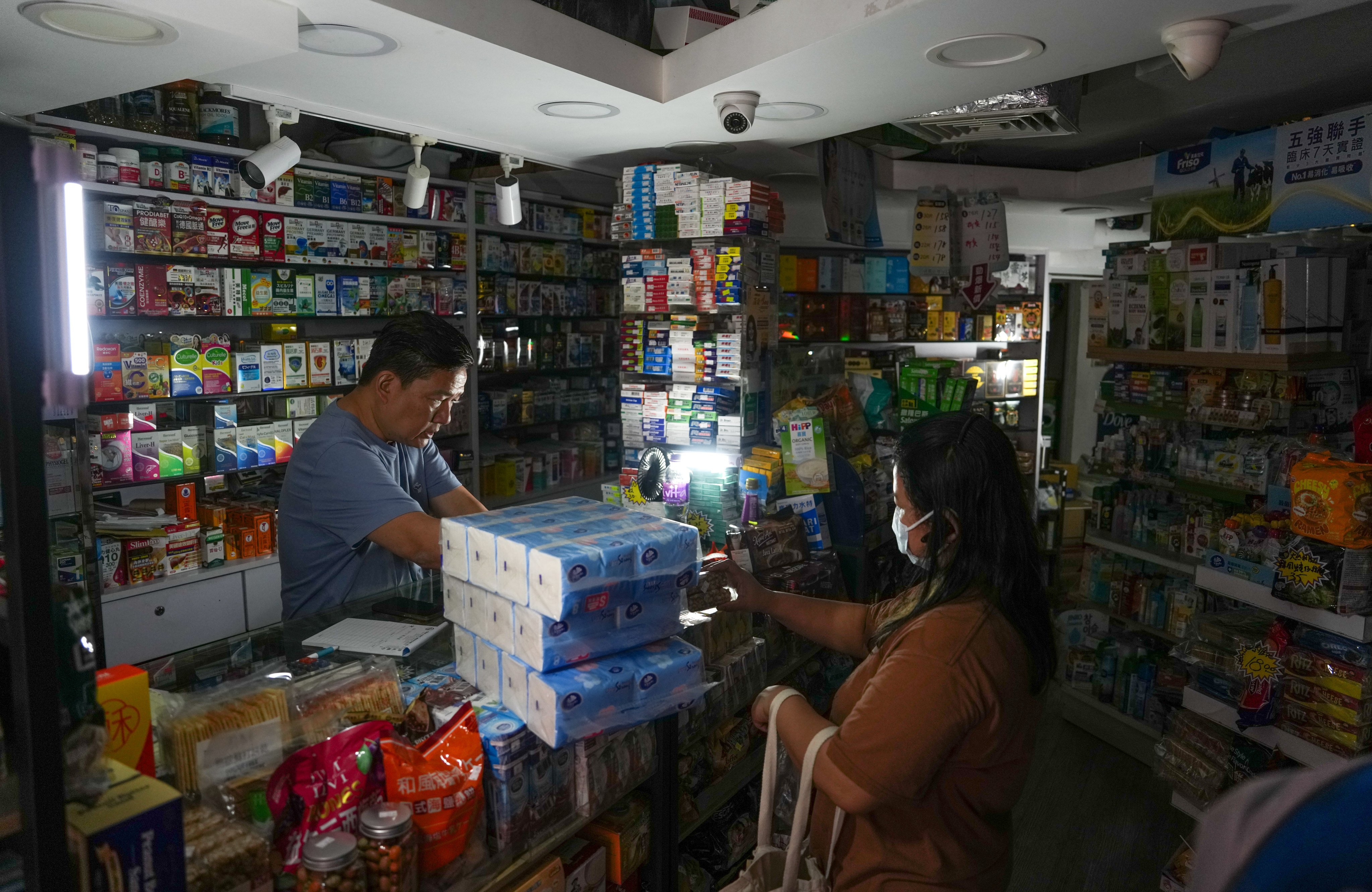 A shopkeeper serves a customer in the dark during a power outage at Tsuen Wan Centre on June 9. The disruption to the supply of electricity and fresh water, caused by an equipment malfunction, affected around 1,000 households. Photo: Sam Tsang