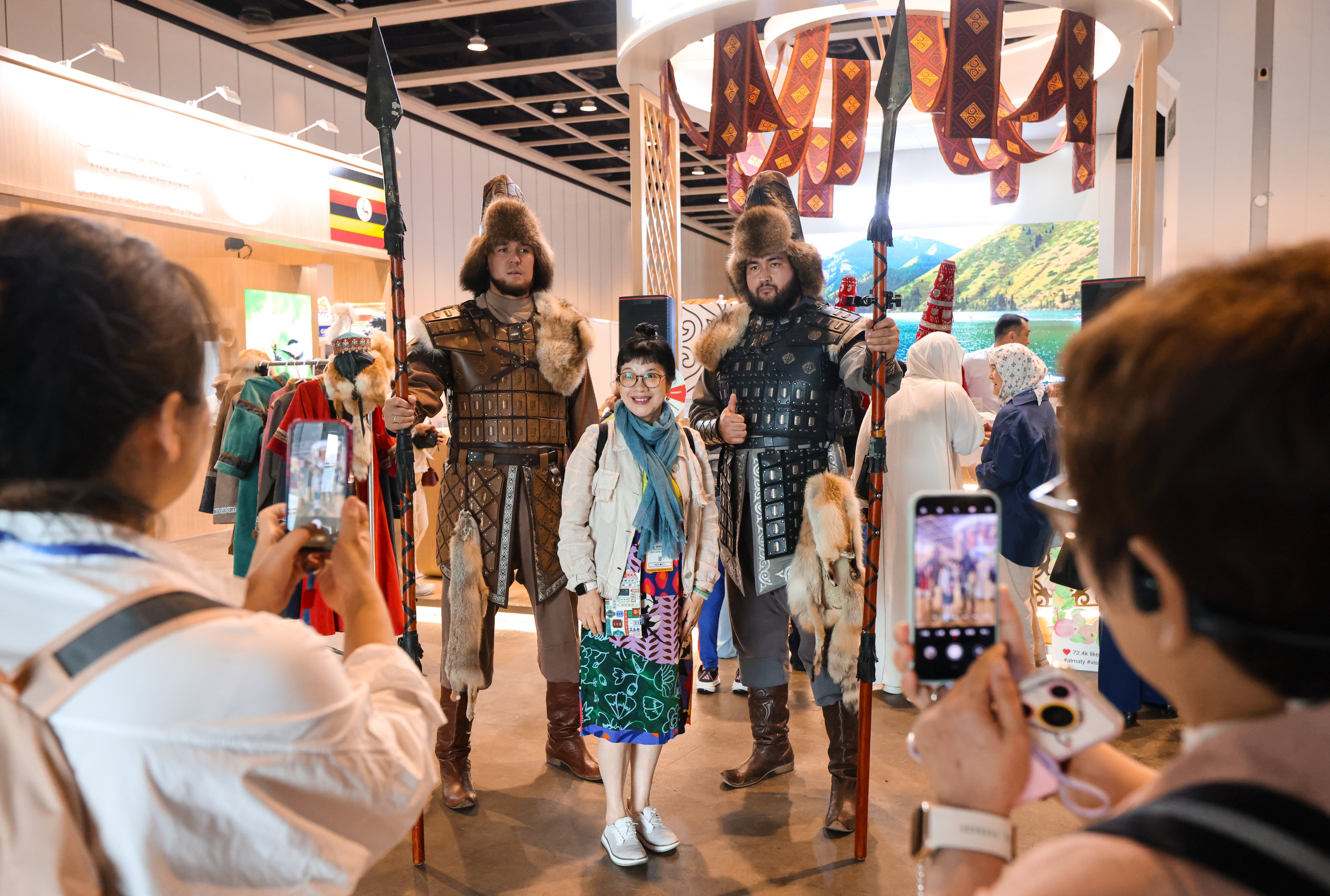 A visitor poses for a picture with two-metre-tall promoters at the “Visit Almaty" booth. Photo: Nora Tam
