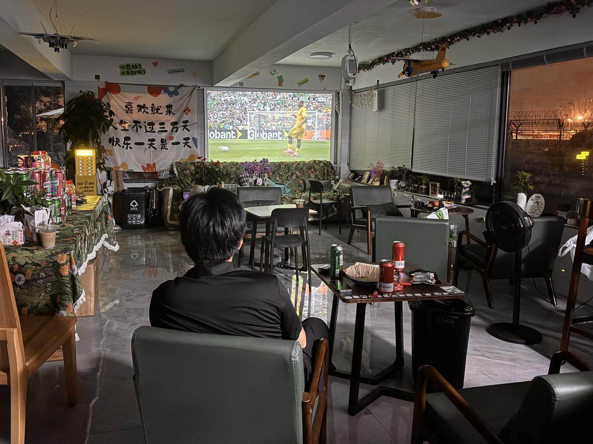 Owner Zhao Chong drinks beer and eats snacks alone as he watches the opening match between Mexico and South Africa at his shop in Hangzhou. Photo: Weibo