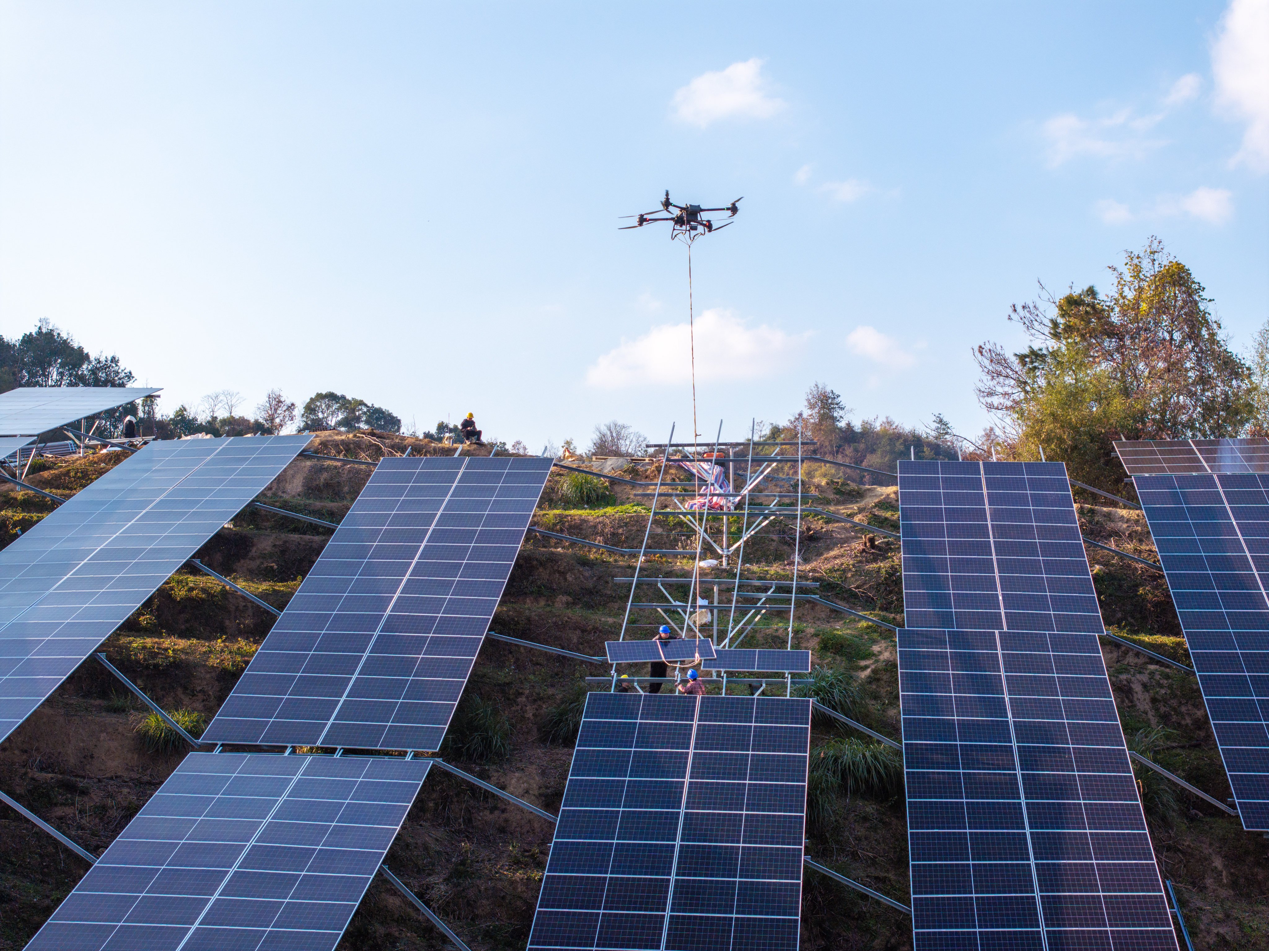 A worker operates a drone to lift solar panels up a hillside in Zhejiang province. Photo: VCG via Getty Images