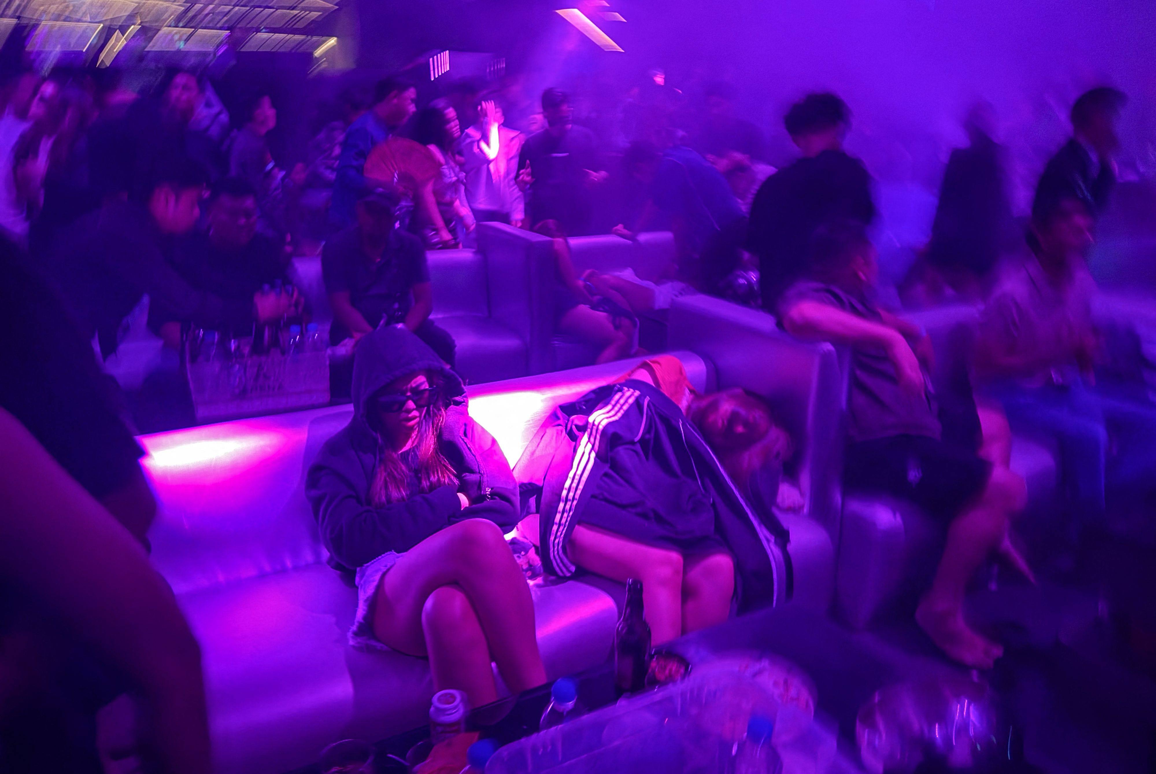 People sleep on a sofa in a nightclub in Yangon while others dance to loud music on May 16 Photo:  AFP
