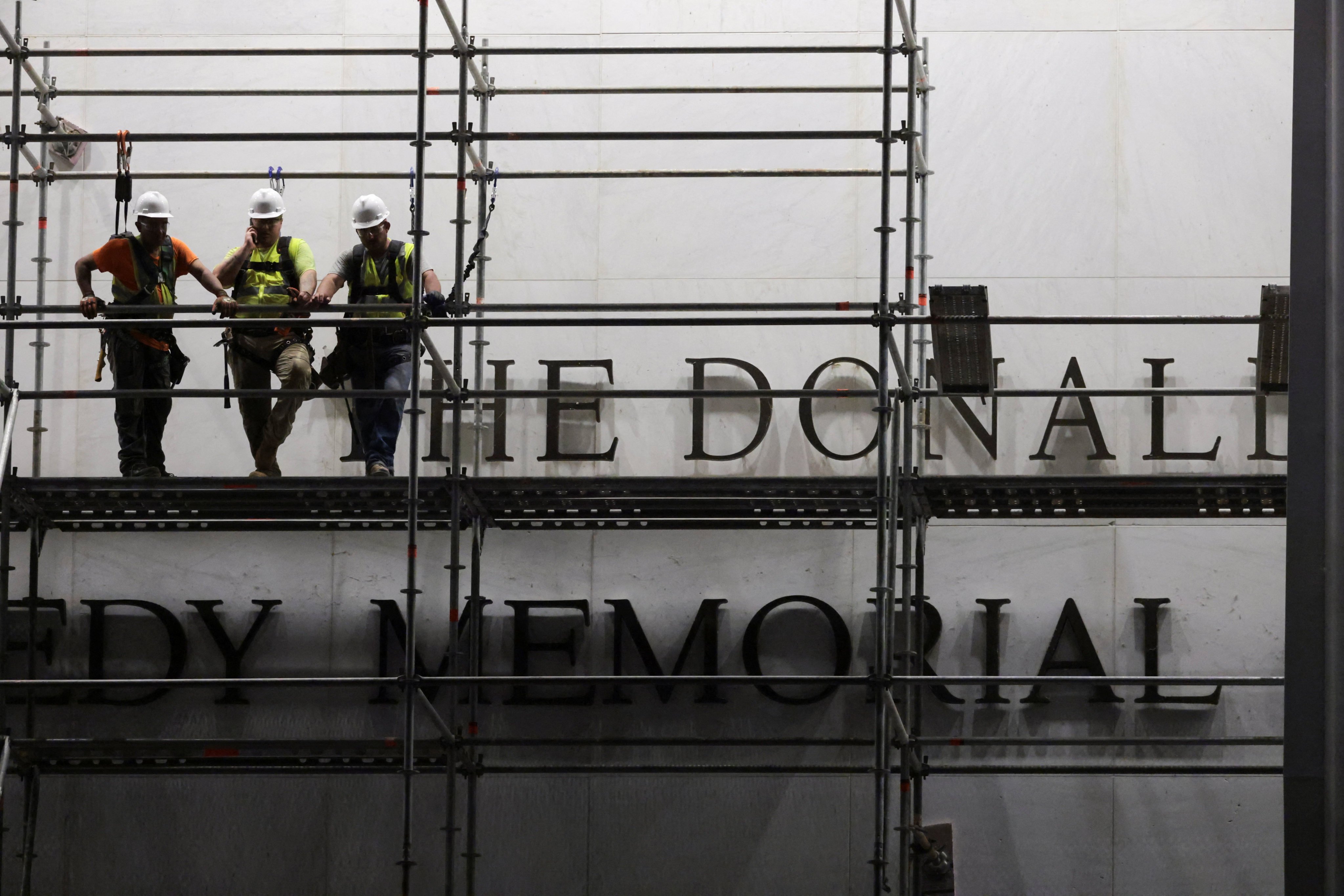 Workers stand on scaffolding ahead of removing lettering from the facade of the John F. Kennedy Memorial Centre for the Performing Arts on Friday. Photo: Reuters