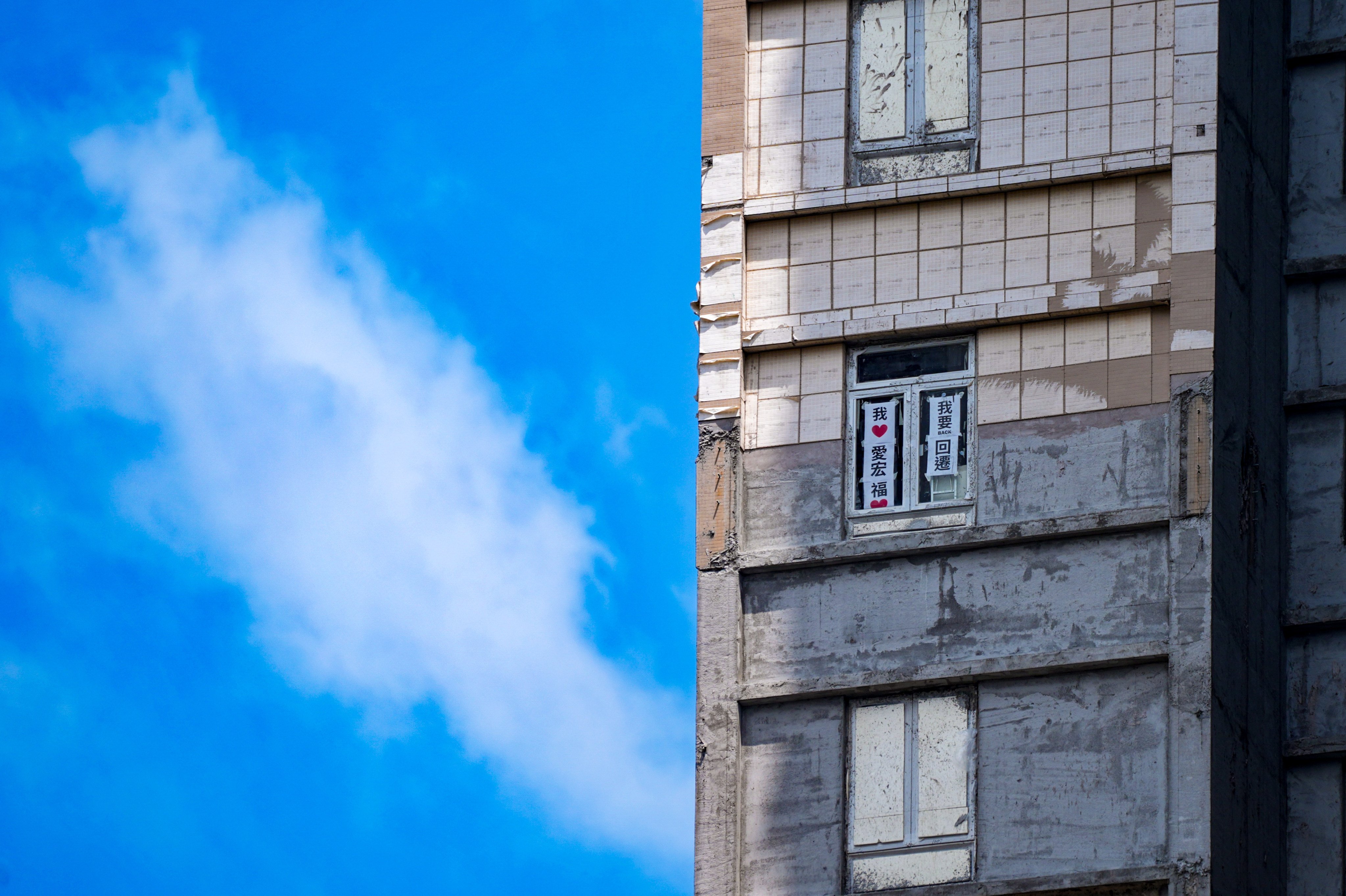 Signs saying “I love Wang Fuk Court” and “I want to move back” are posted on the windows of a flat at the fire-ravaged estate in Tai Po. Photo: Elson Li