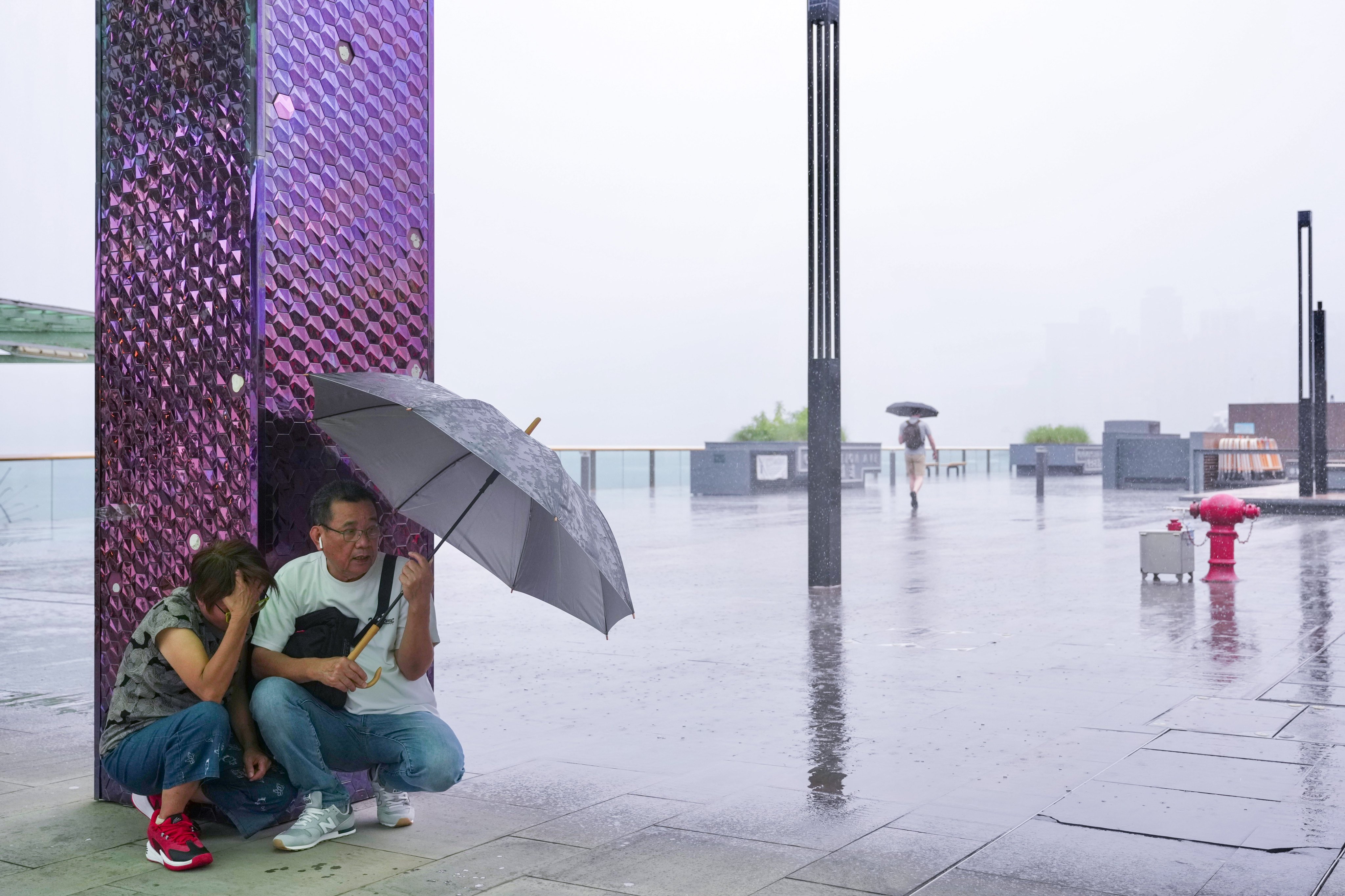 Two residents shelter under an umbrella during the heavy rain. Photo: Karma Lo