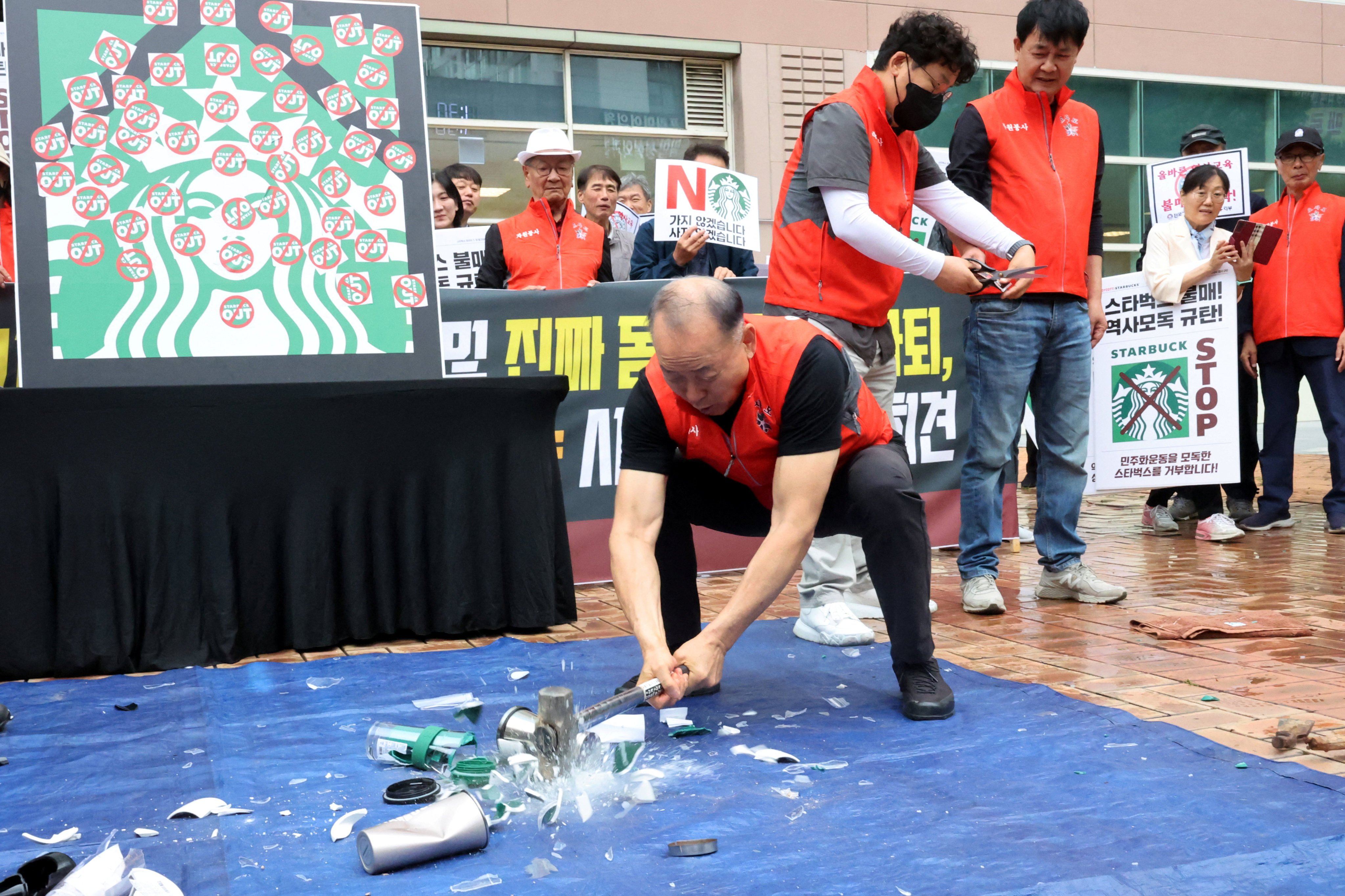 An activist smashes Starbucks tumblers and mugs during a protest against its “Tank Day” campaign on May 21. Photo: Yonhap/Reuters