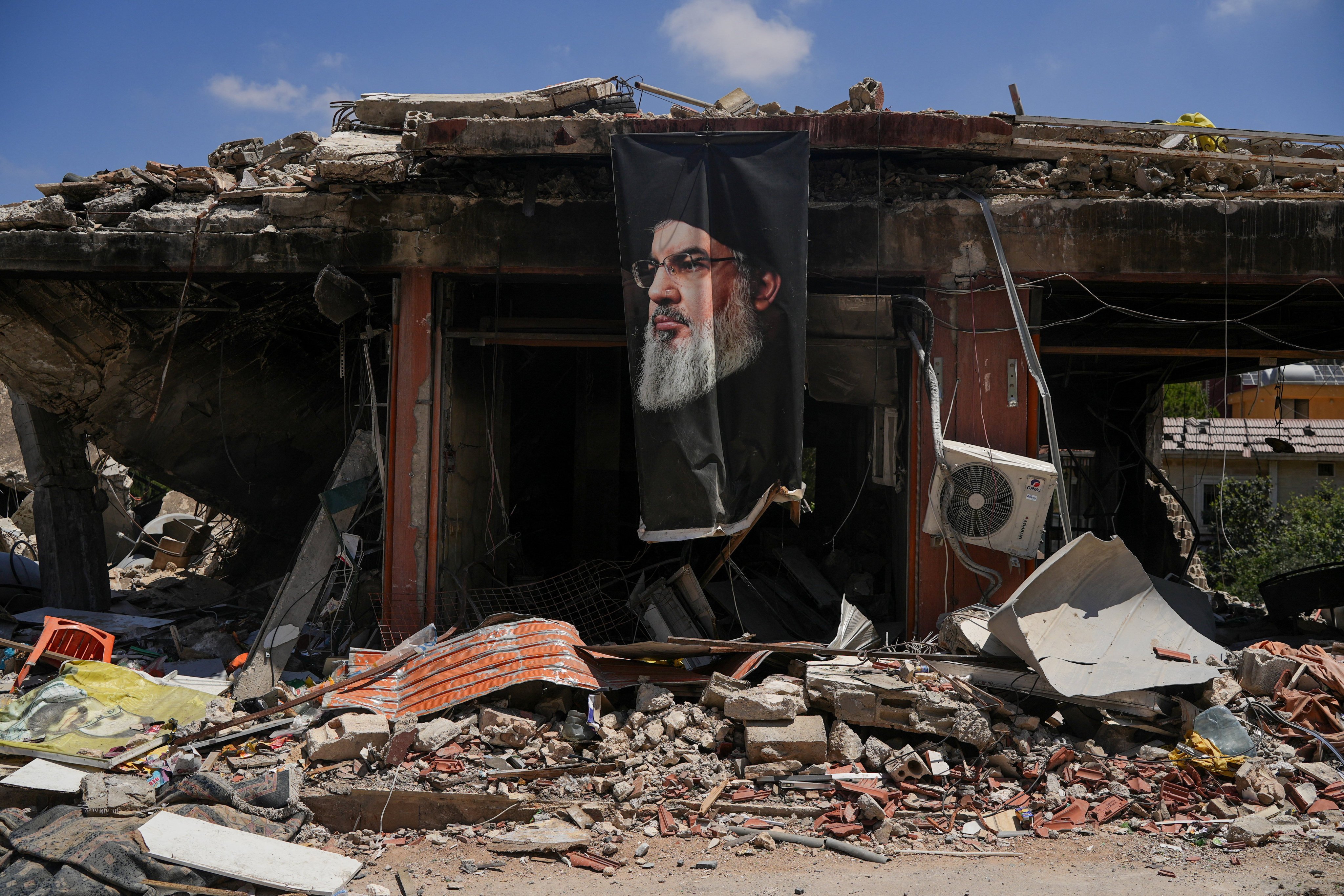 A banner with an image of late Hezbollah leader Hassan Nasrallah hangs from a building destroyed in an air strike in Jibchit, Lebanon, on Tuesday. Photo: Reuters
