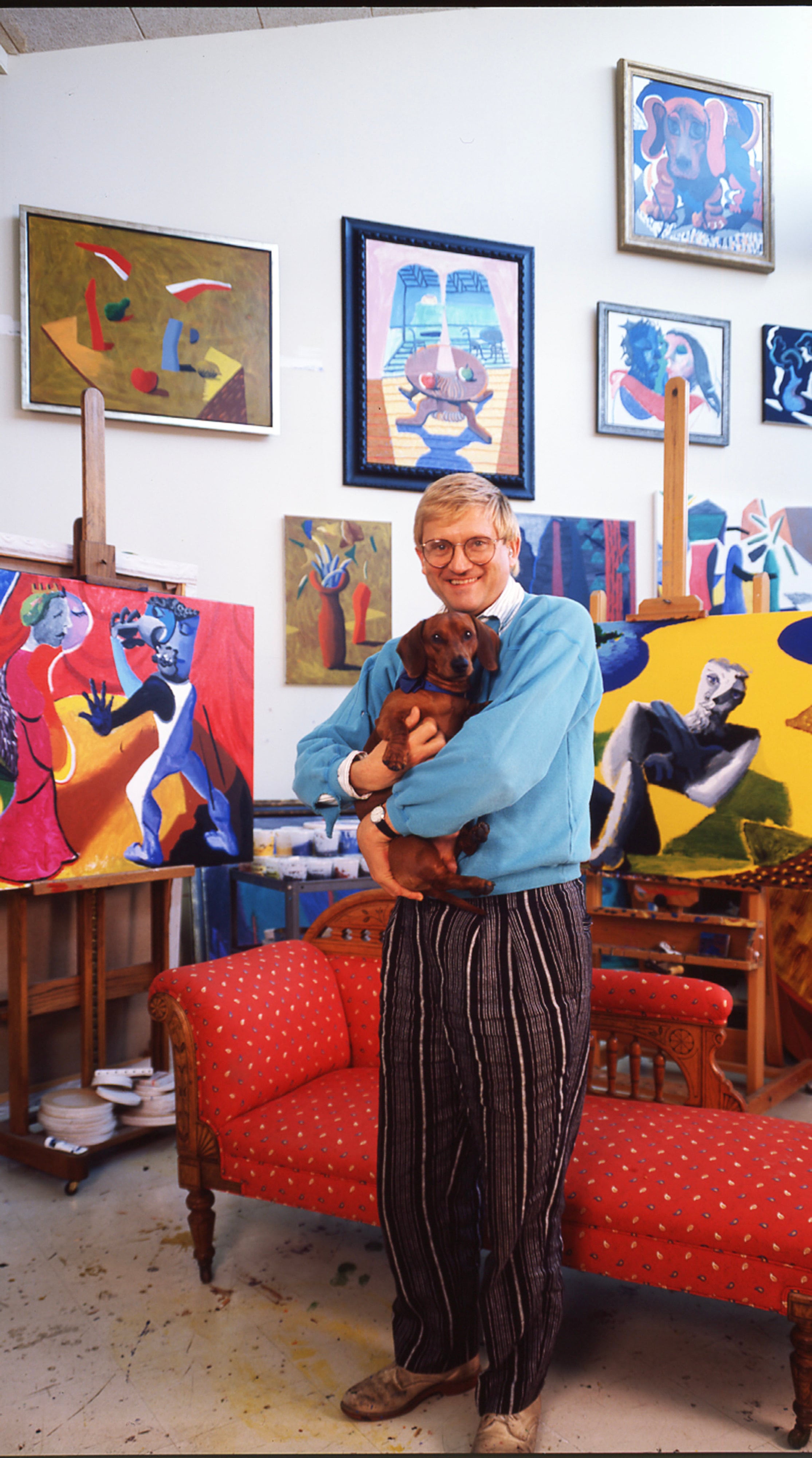 British artist David Hockney, with one of his dogs in his arms, at home in Los Angeles, California, in 1987. Photo: Getty Images