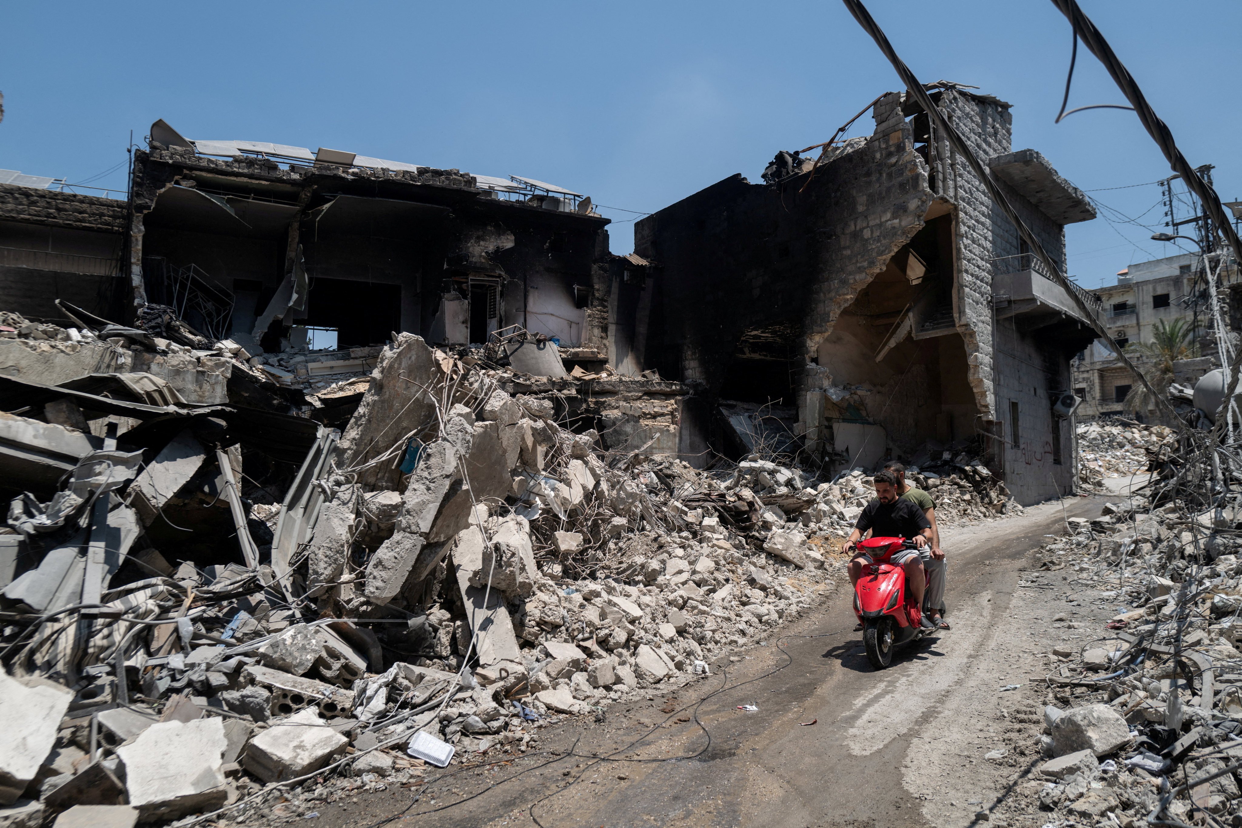 Men ride a motorcycle past buildings damaged by Israeli strikes in Nabatieh, Lebanon, on Wednesday. Photo: Reuters