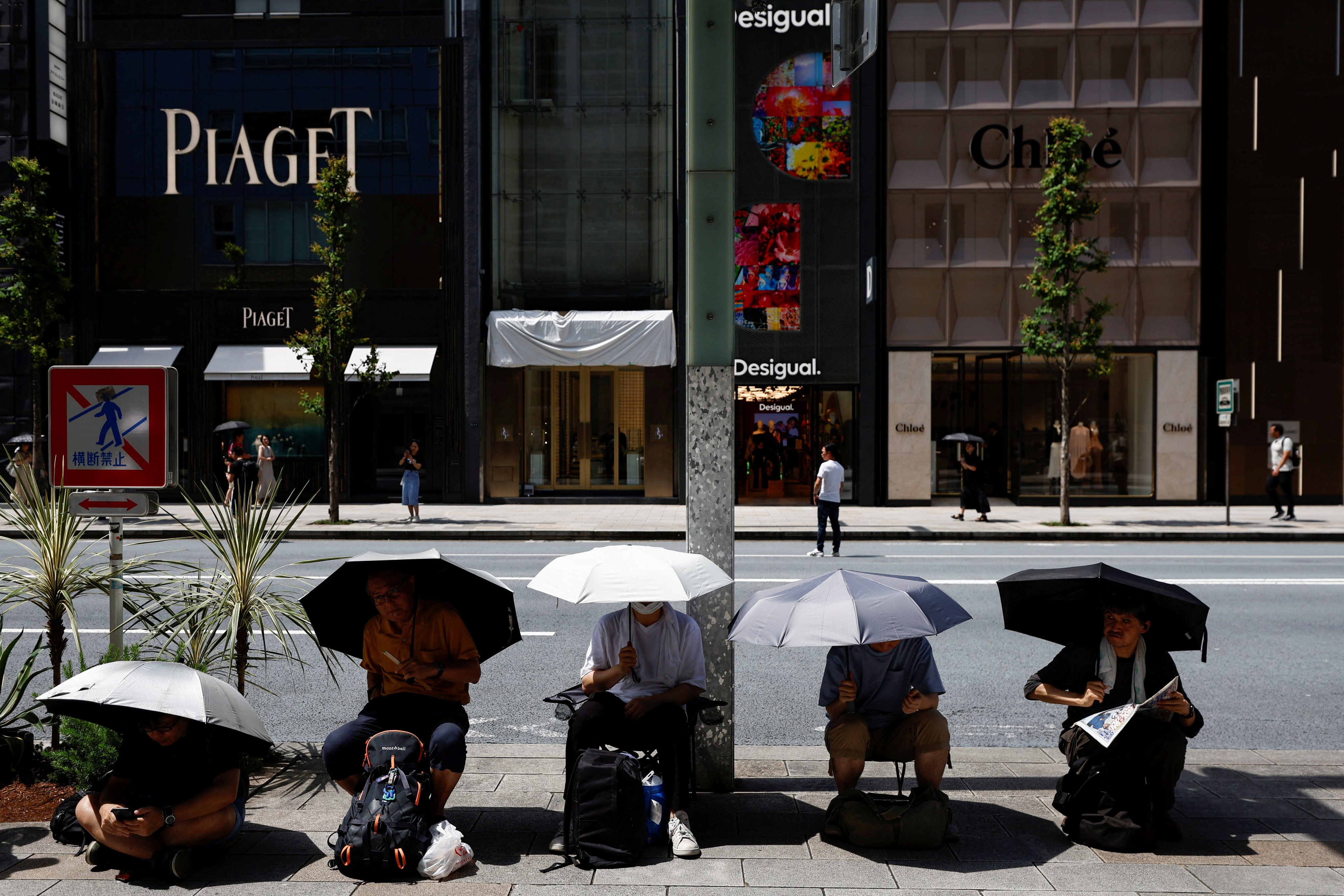People cover themselves with umbrellas during a hot summer day at Ginza in Tokyo on August 11, 2024. Photo: Reuters