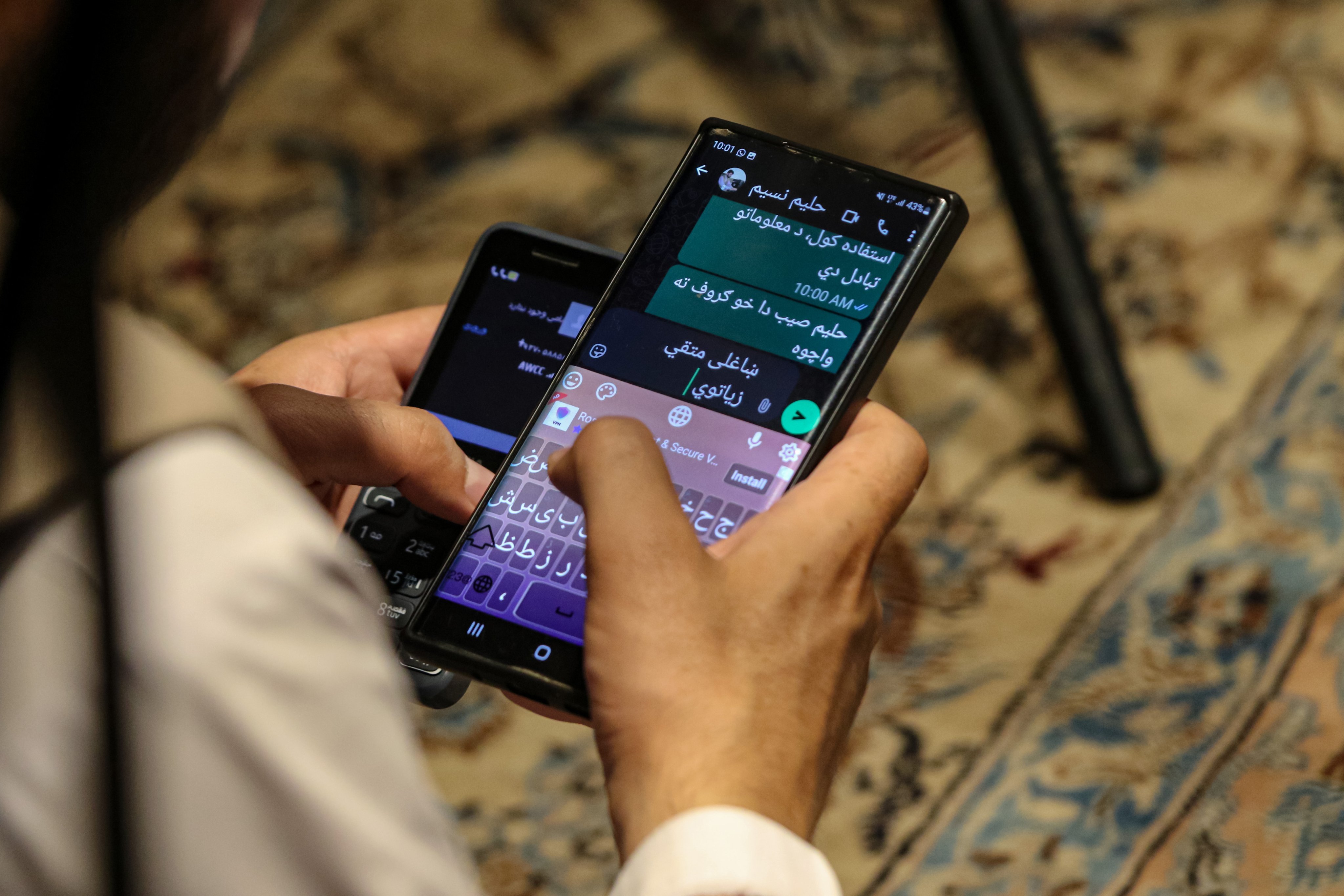 A man uses smartphones in Kabul on Tuesday. Photo: EPA