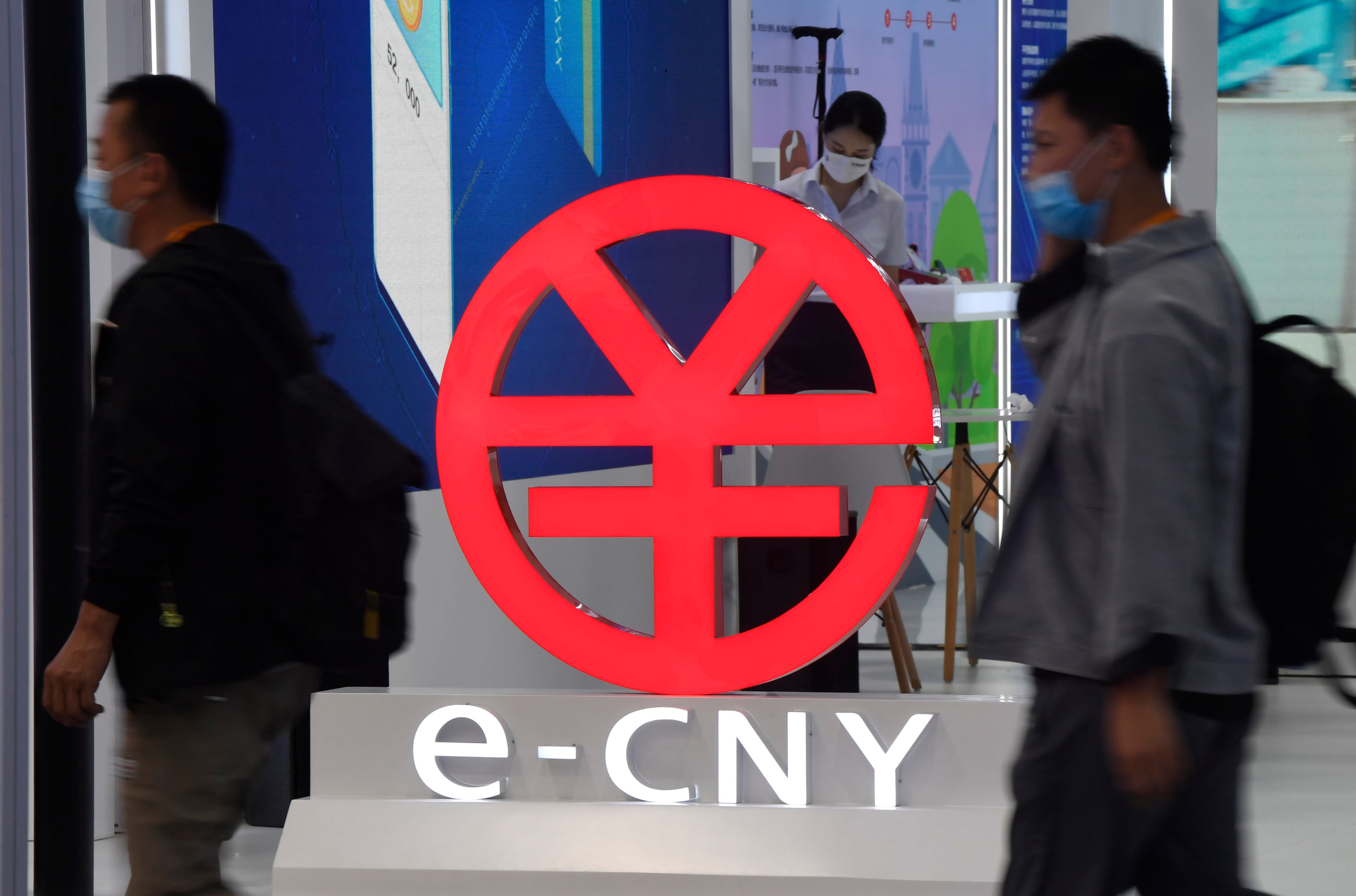 People walk past a sign promoting the digital yuan, or e-CNY, at an expo in Beijing. Photo: Xinhua