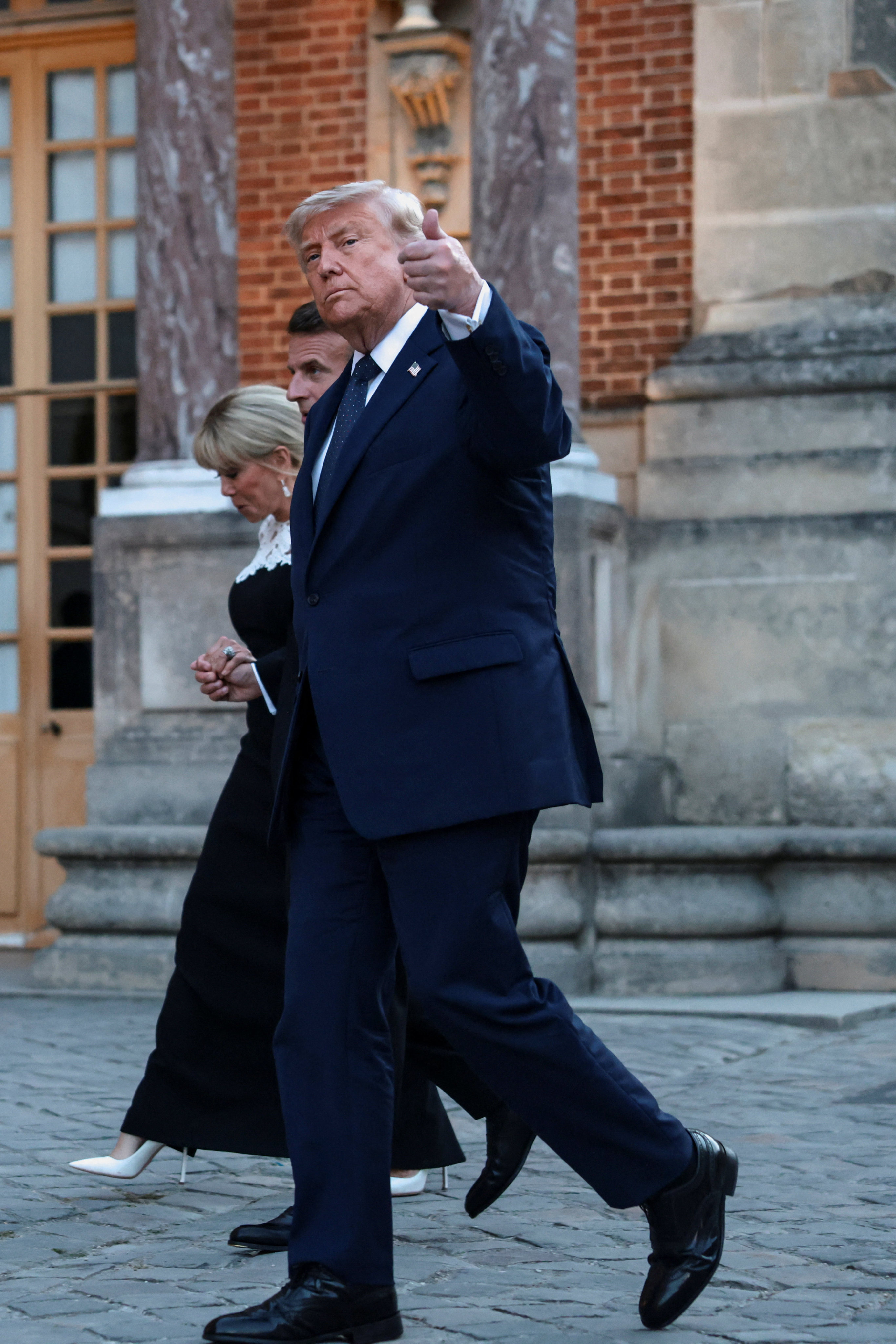 U.S. President Donald Trump gives a thumbs up as he walks with French President Emmanuel Macron and his wife Brigitte Macron ahead of a dinner commemorating the 250th anniversary of the United States' independence, at the Palace of Versailles, near Paris, France, June 17, 2026. REUTERS/Evelyn Hockstein