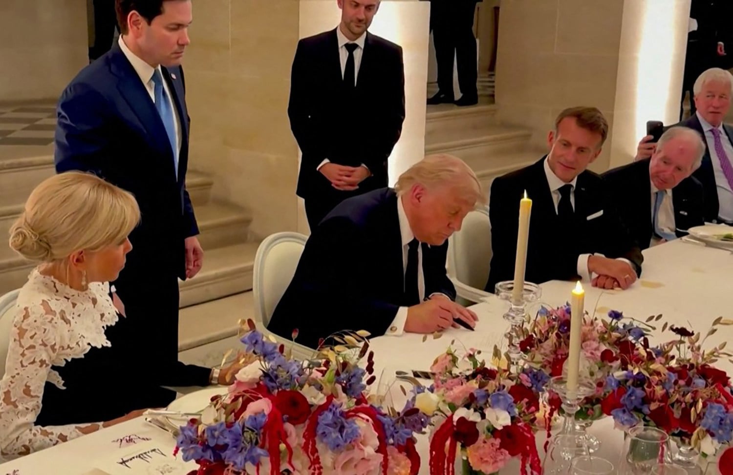 US President Donald Trump (centre) signs a memorandum of understanding with Iran in Versailles, France on June 17 as French President Emmanuel Macron (right) and his wife Brigitte Macron (left) look on. Photo: AFP and X/Scavino47