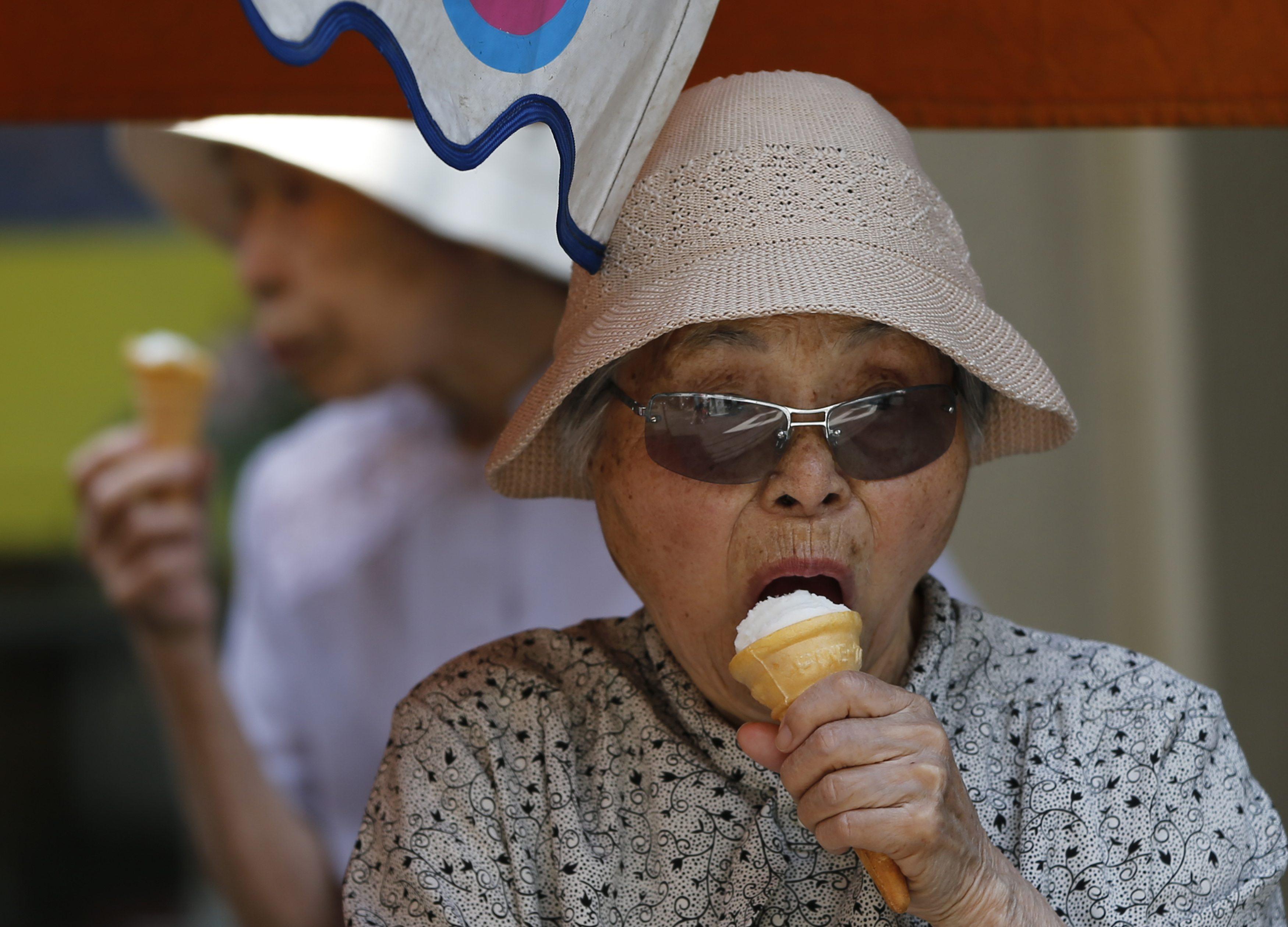 Elderly women eat ice cream at Tokyo's Sugamo district, an area popular among the Japanese elderly, in Tokyo June 4, 2013. Japan's government is set to urge the nation's public pension funds - a pool of over $2 trillion - to increase their investment in equities and overseas assets as part of a growth strategy being readied by Prime Minister Shinzo Abe, according to people with knowledge of the policy shift. REUTERS/Issei Kato (JAPAN - Tags: POLITICS BUSINESS EMPLOYMENT)