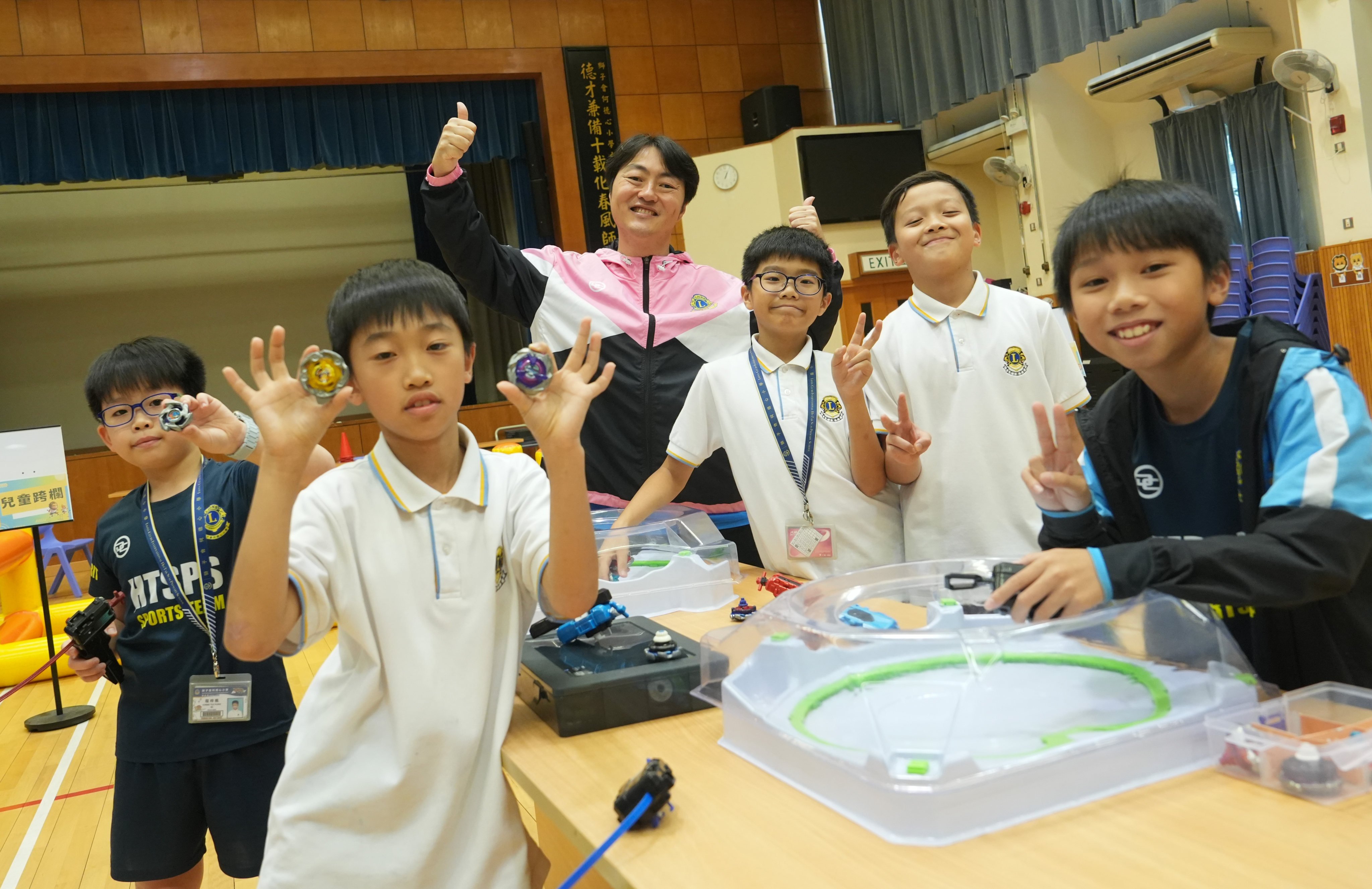 Lions Clubs International Ho Tak Sum Primary School Principal Wong Wai-Lap (third from left) with students playing Beyblade in the school hall. Photo: Sun Yeung