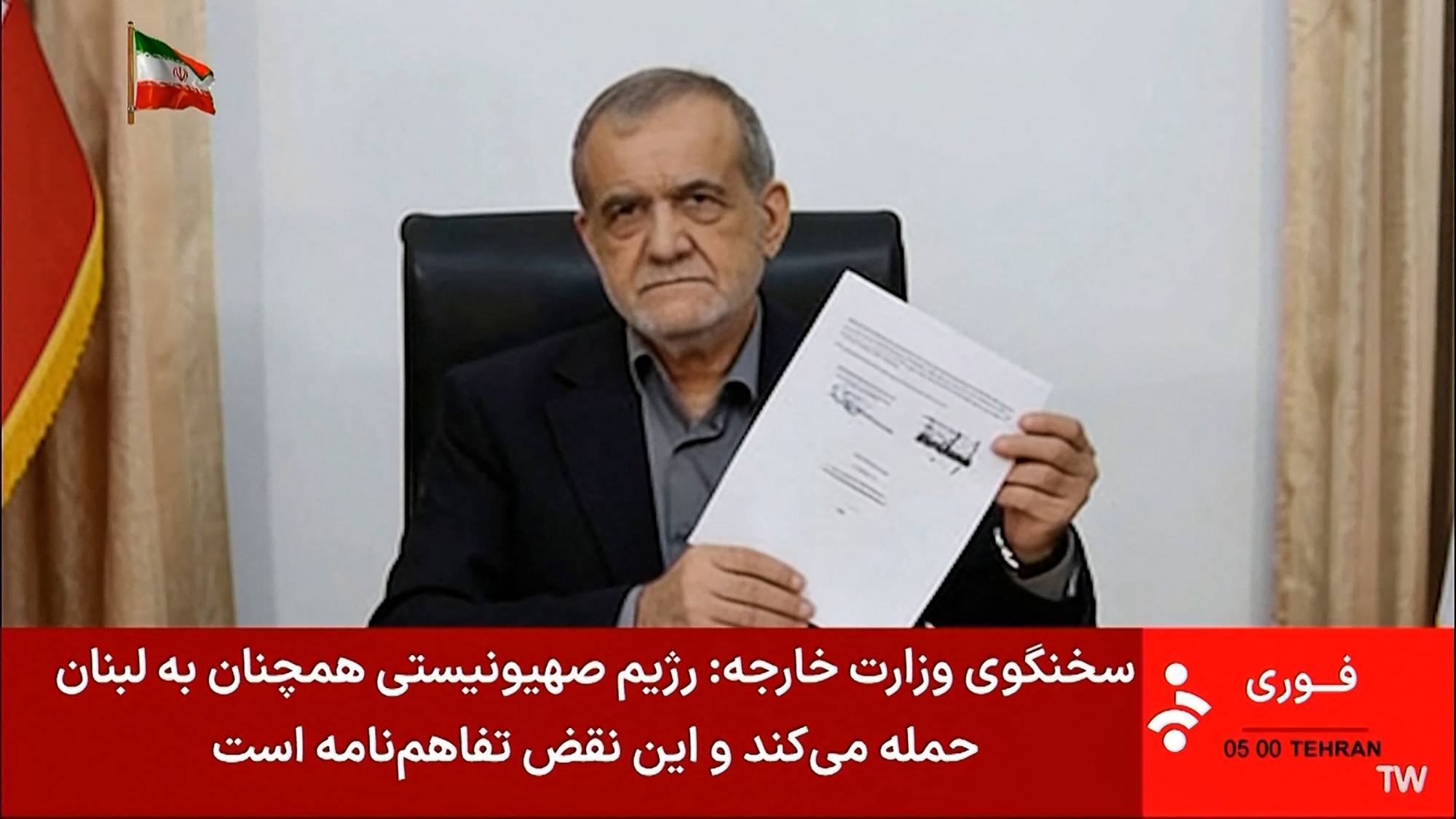 Iran’s President Masoud Pezeshkian holding a document showing a memorandum of understanding he signed. Photo: AFP