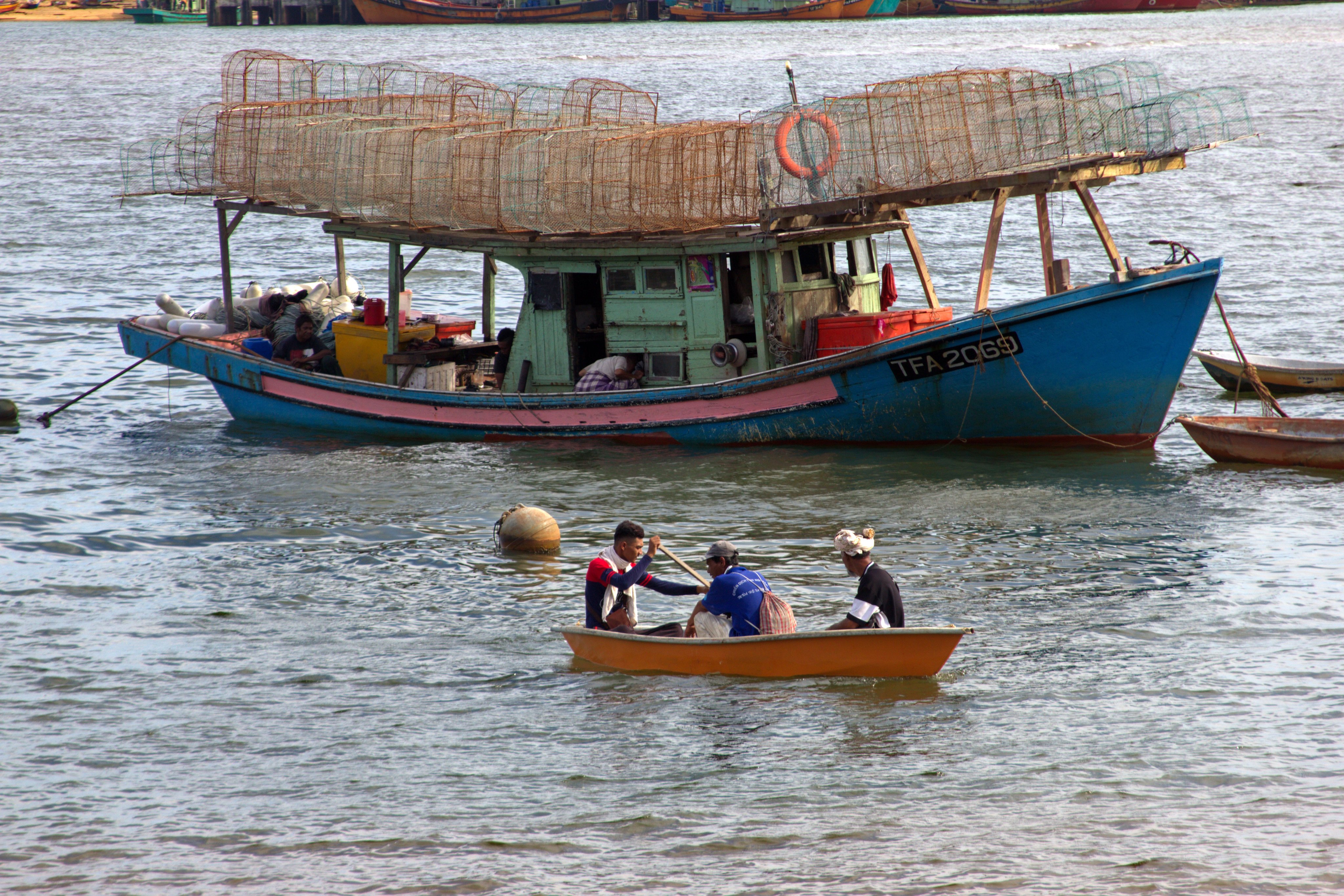 Men row a sampan in front of a local fishing boat in Terengganu, Malaysia. Photo: Keith Mundy