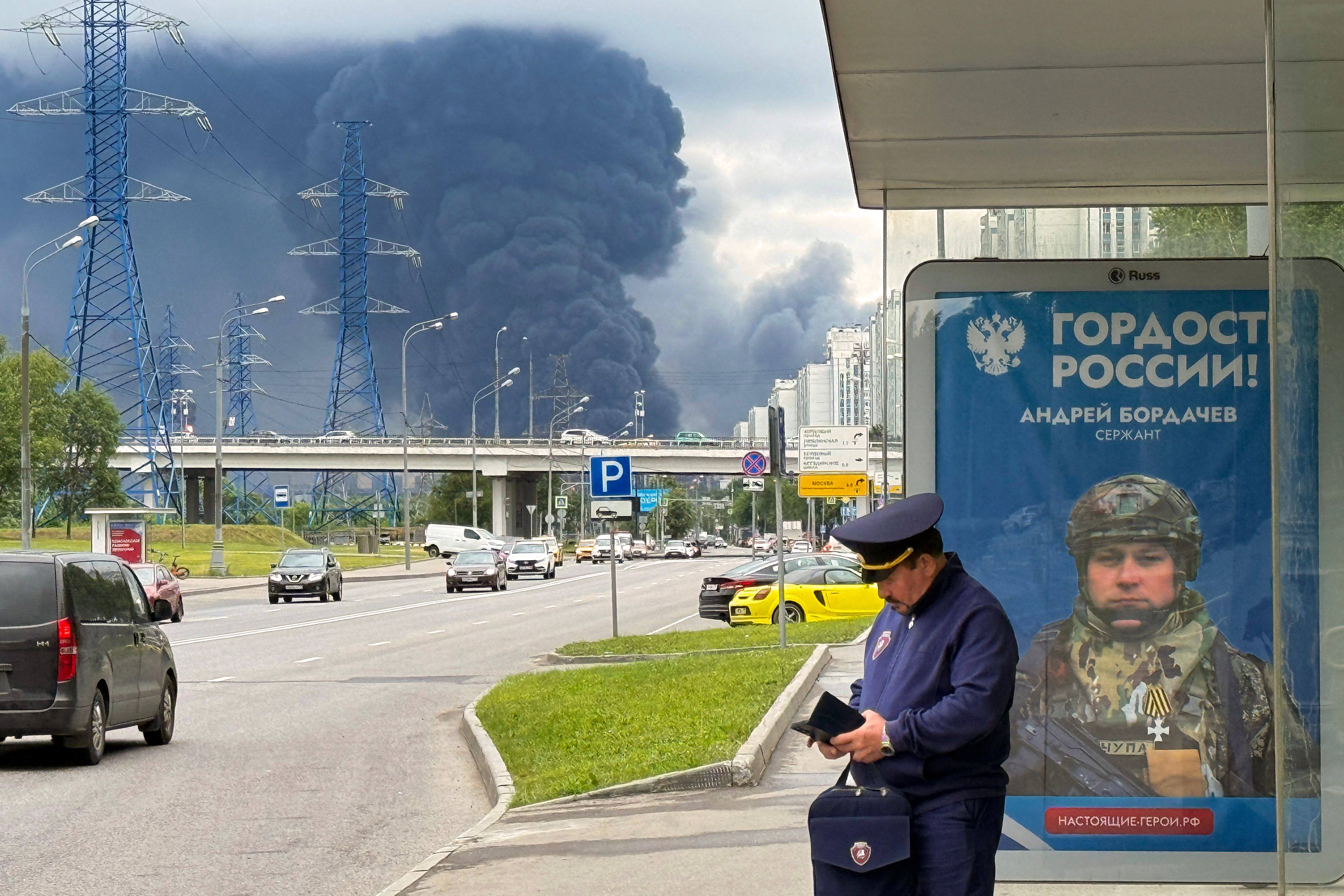 Muscovites go about their daily life as black smoke rises from an oil refinery following a Ukranian drone attack on Thursday. Photo: AFP