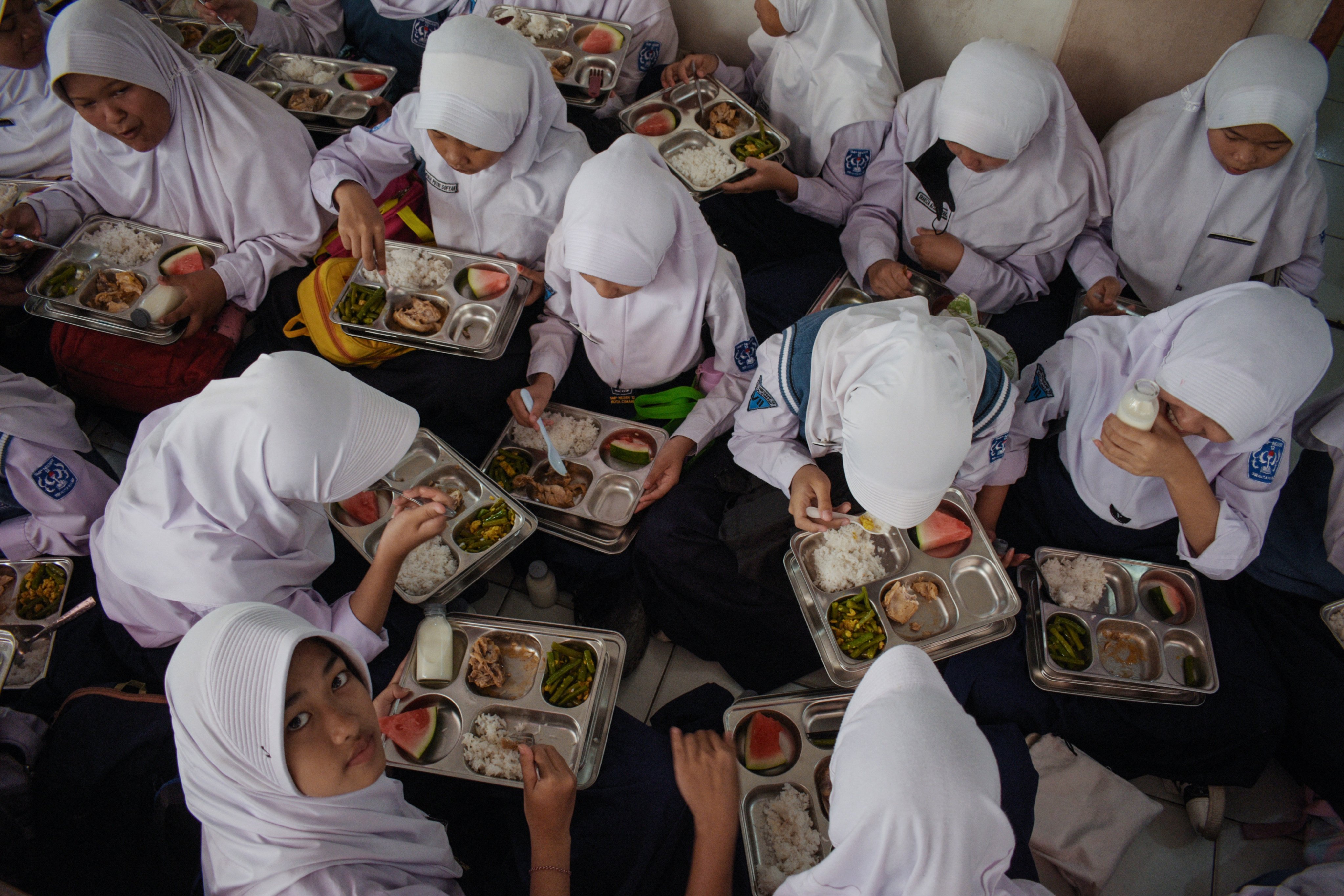 Students eat lunch on the first day of a free-meal programme at 12 State junior high school in Cimahi, West Java, on January 6, 2025. Indonesia launched an ambitious USD 4.3 billion free-meal programme on January 6 to combat stunted growth due to malnutrition, a key election promise of President Prabowo Subianto. (Photo by Timur MATAHARI / AFP)