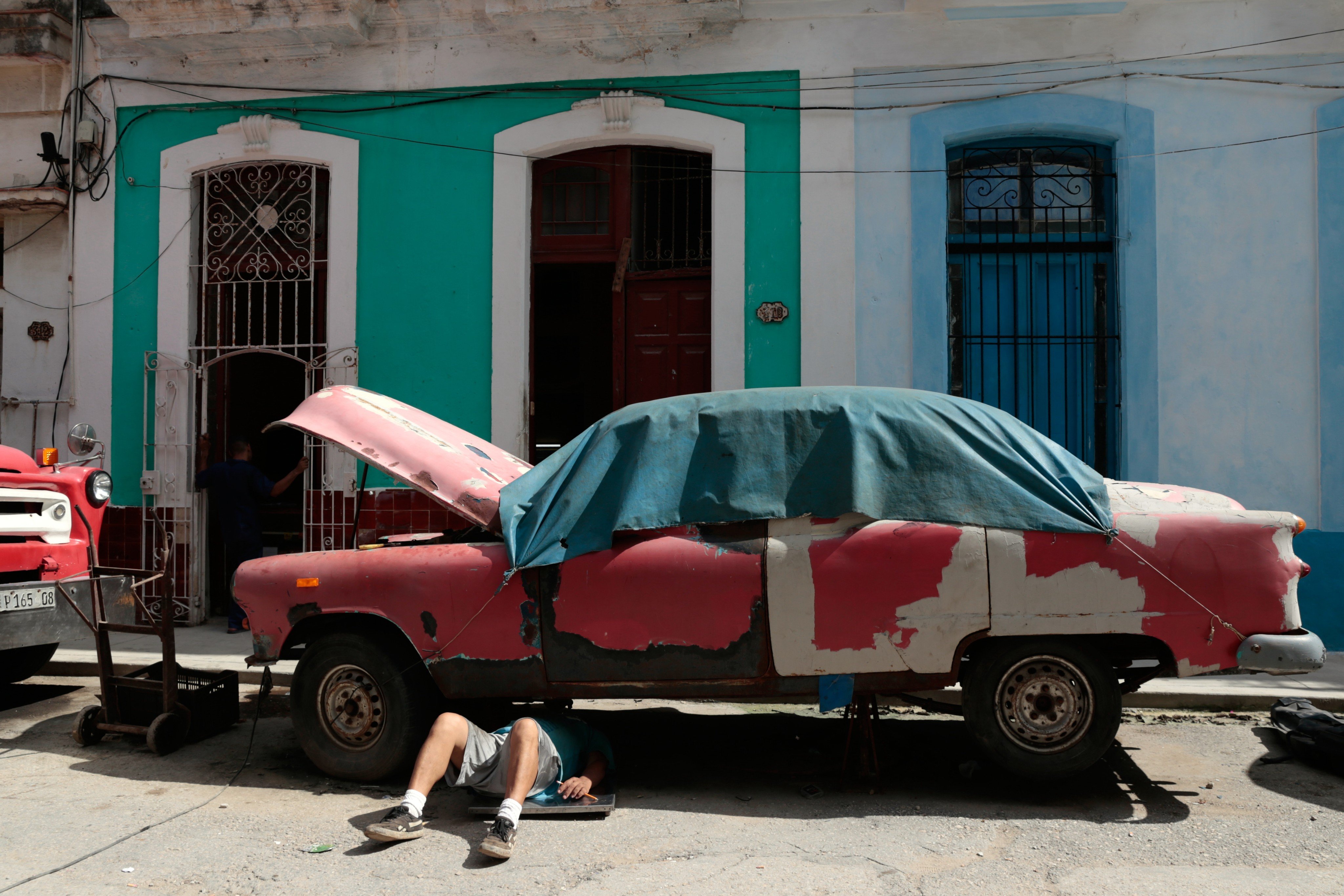 A man works on a classic American car in Havana. The communist island has unveiled its most profound free-market reforms in decades. Photo: AP