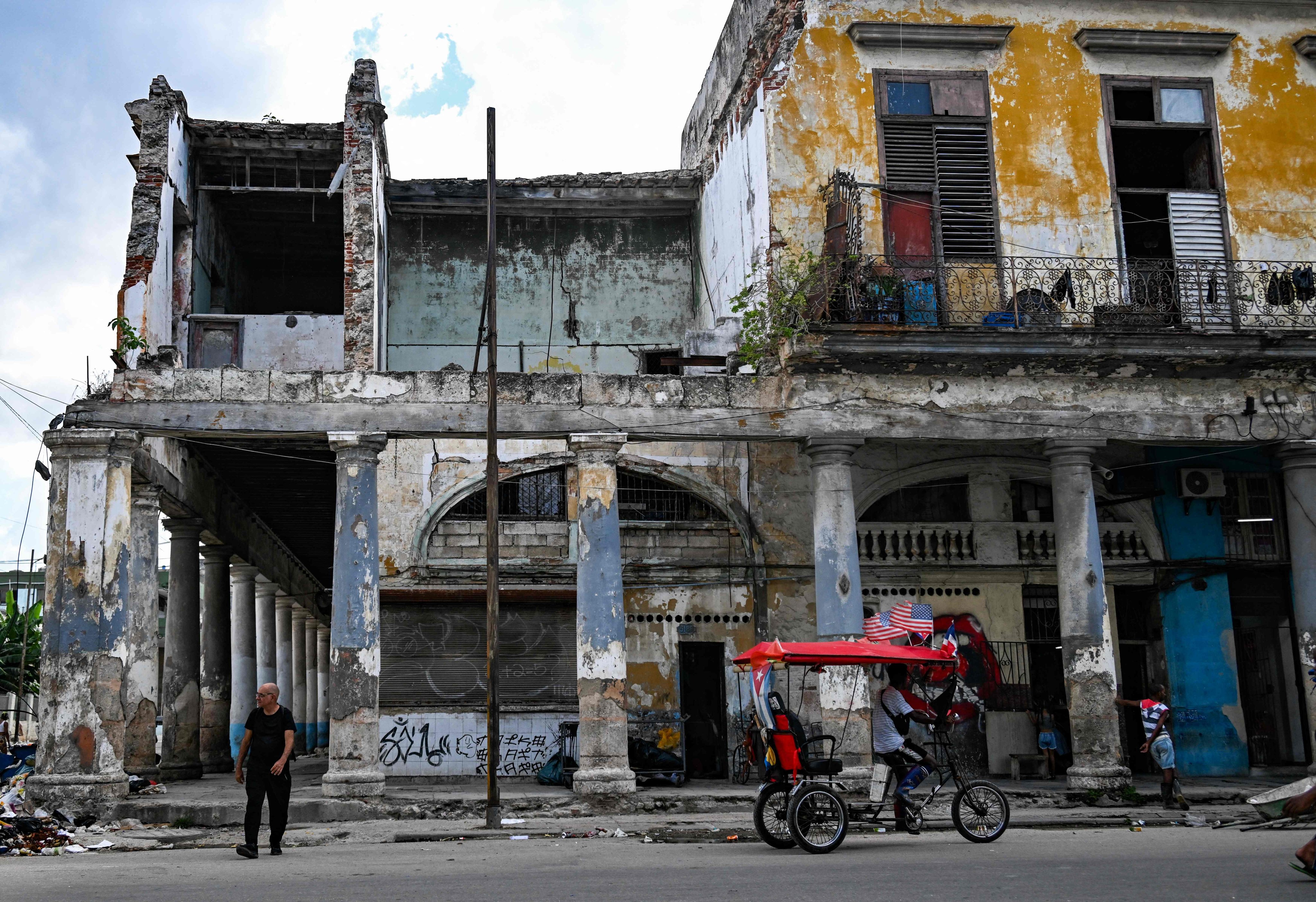 A tricycle taxi passes a building at risk of collapse in Havana on Monday. Photo: AFP