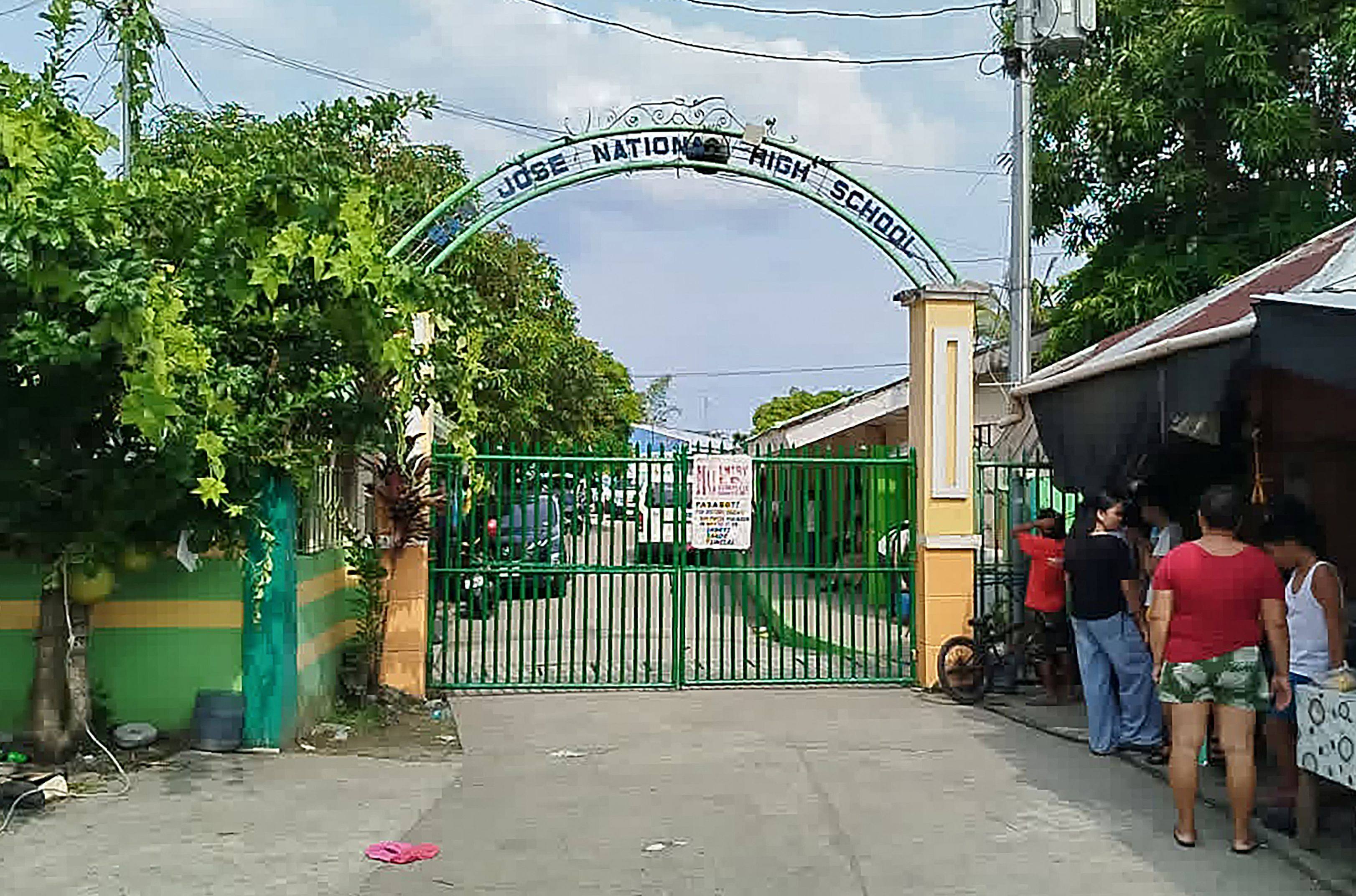 People stand next to the entrance gate of San Jose National High School after a shooting incident in Tacloban City, Leyte province, the Philippines, on Monday. Photo: AFP
