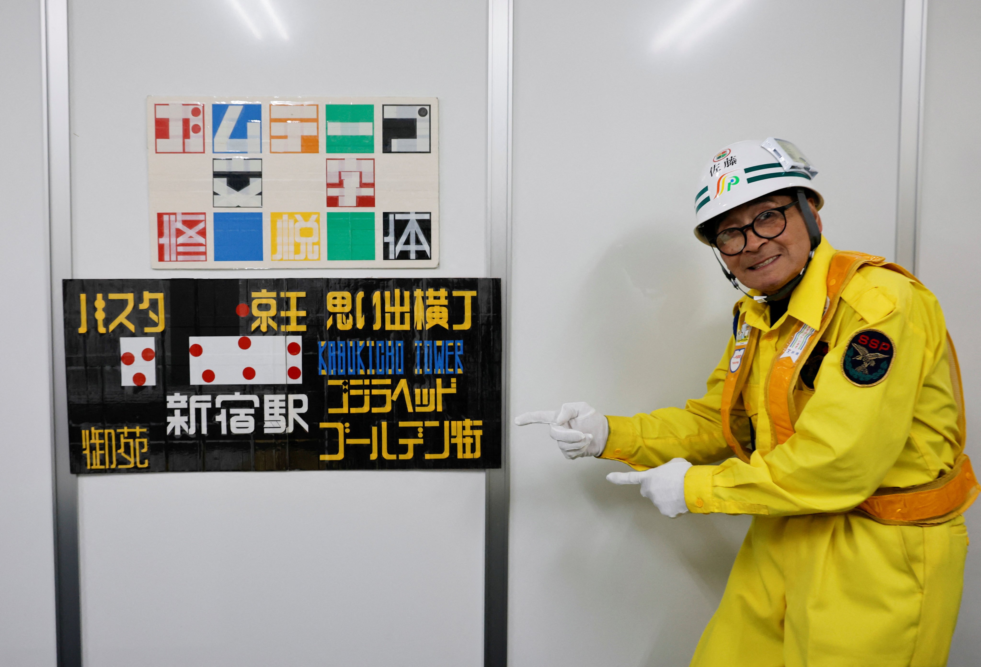 Shuetsu Sato, a security guard, poses with the famed duct-tape signs he made by hand at a company office in Tokyo, Japan. Photo: Reuters
